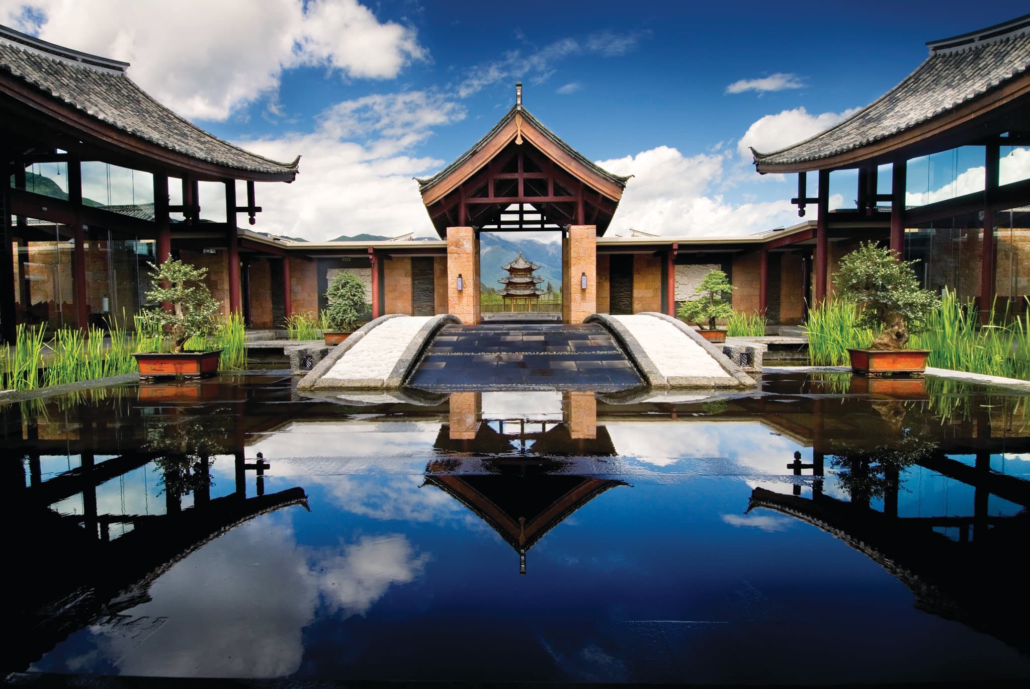 A traditional Naxi-style villa courtyard at Banyan Tree Lijiang featuring a private jet pool with the Jade Dragon Snow Mountain looming in the background.