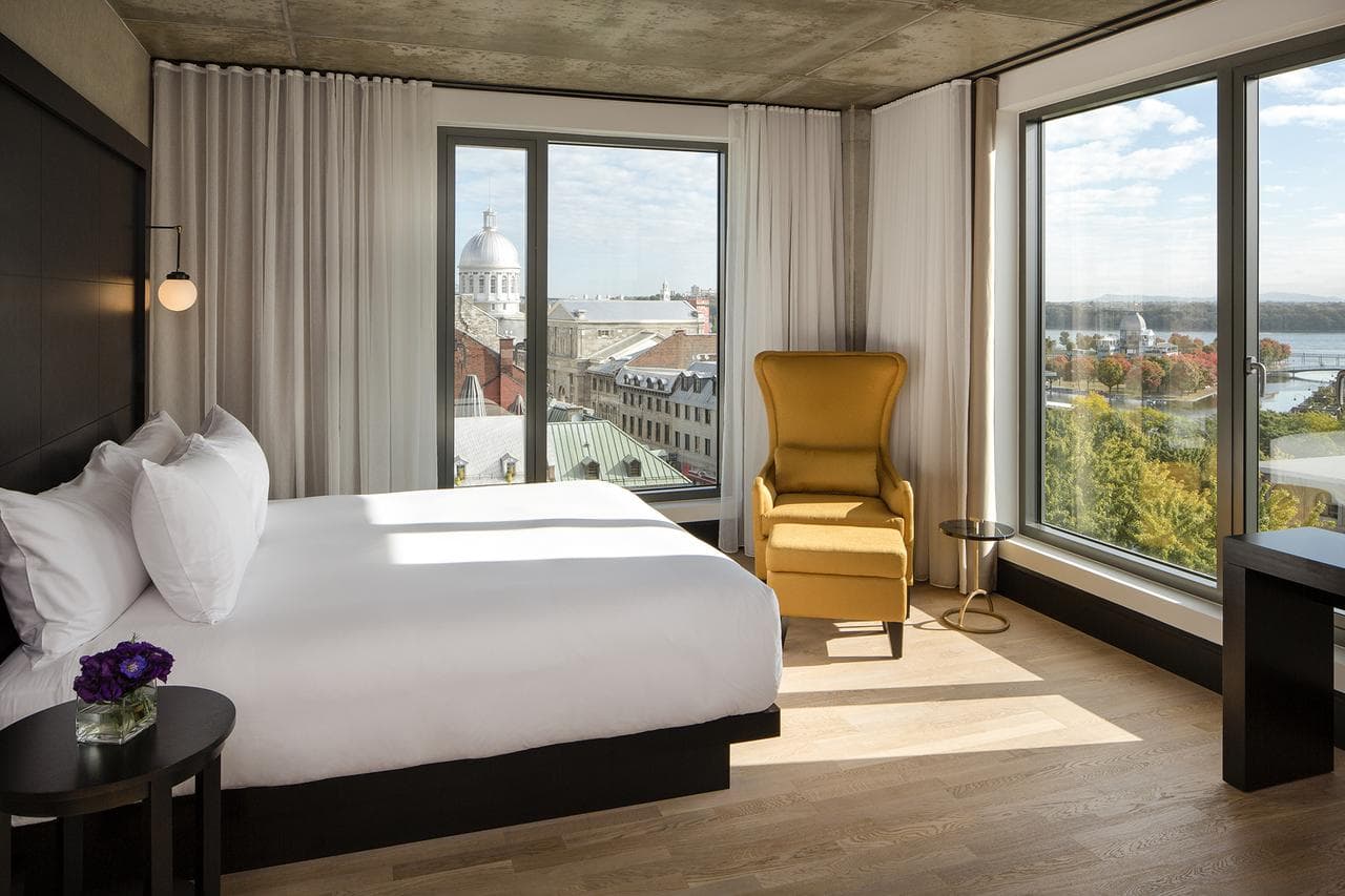 A modern glass atrium connecting two historic limestone buildings at Hôtel William Gray, featuring a buzzy lobby lounge with pool tables.