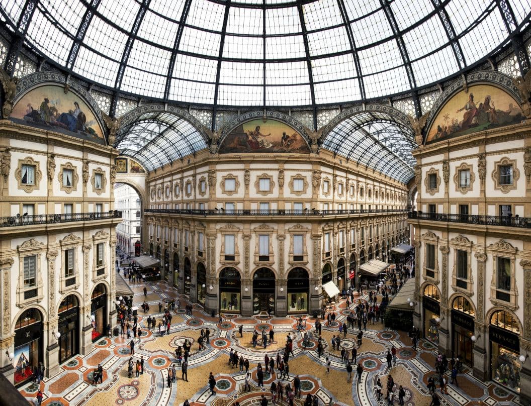 A vibrant, mural-covered bedroom at Galleria Vik Milano featuring a private balcony overlooking the intricate mosaic floor of the Galleria Vittorio Emanuele II.