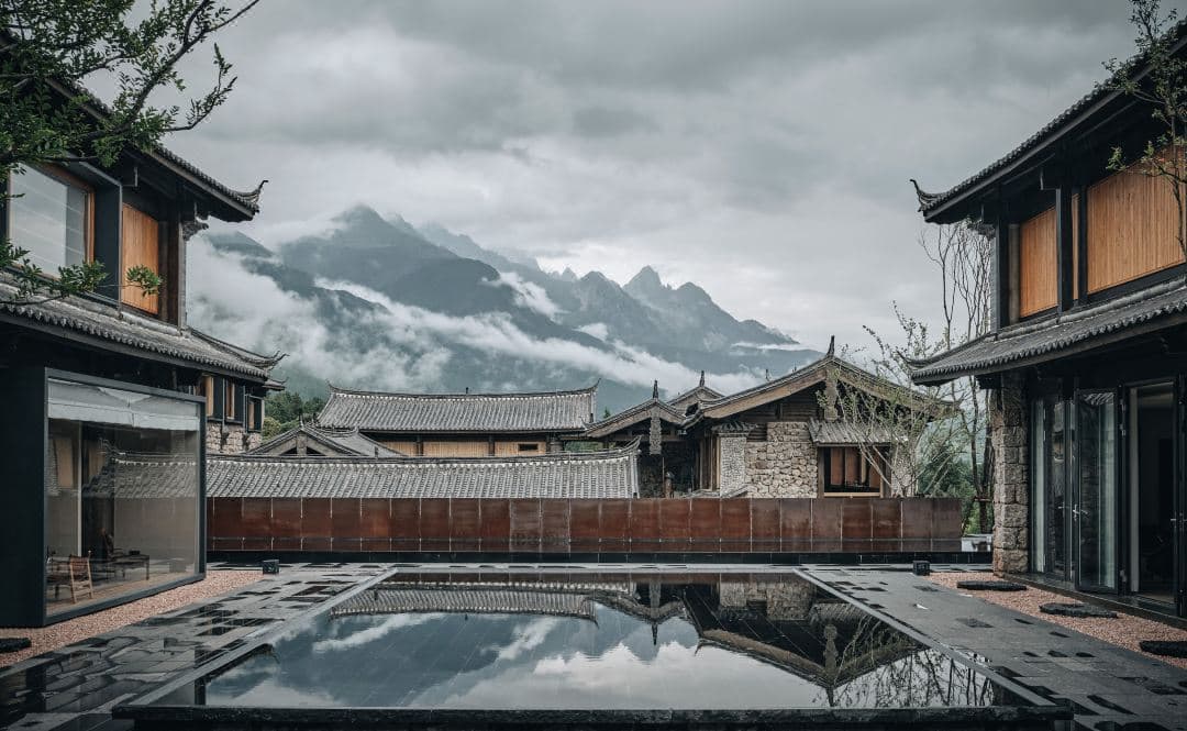A vintage Finn Juhl chair facing a floor-to-ceiling window framing the Jade Dragon Snow Mountain at Hylla Vintage Hotel.