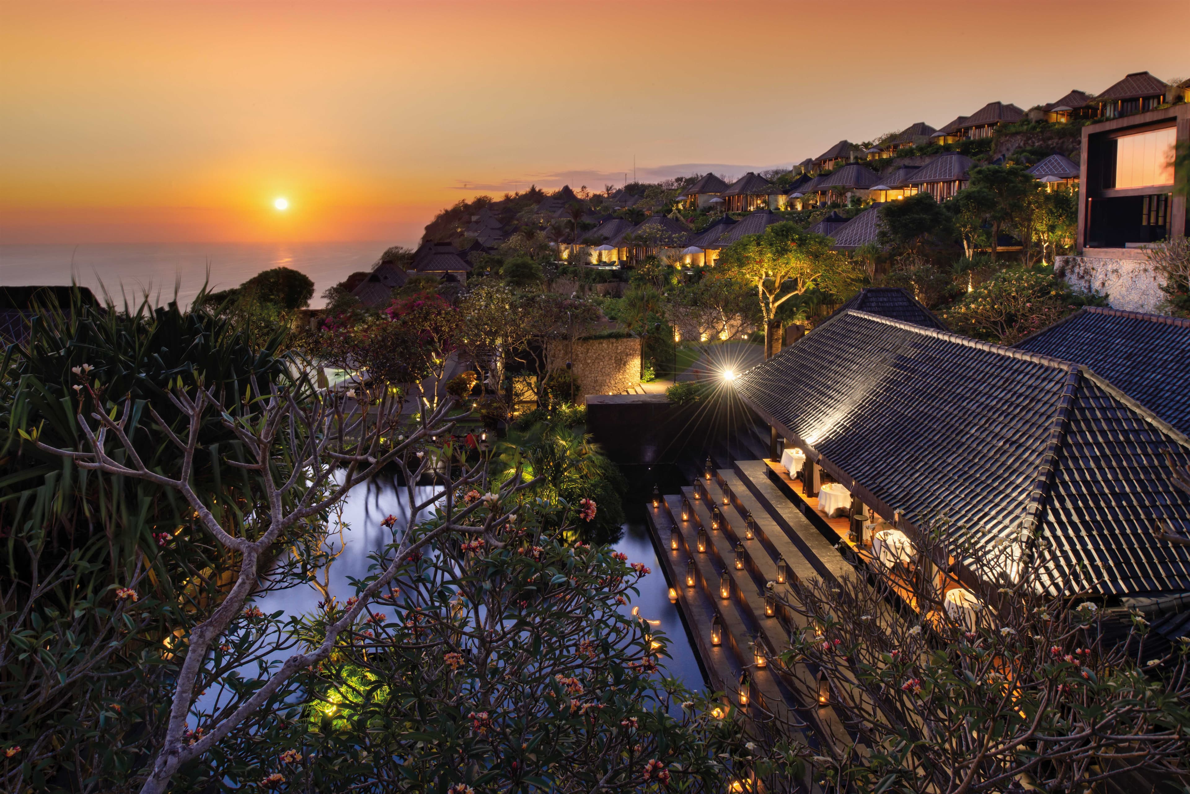 A dramatic view of the Bulgari Resort Bali infinity pool merging with the Indian Ocean, framed by dark volcanic stone architecture.