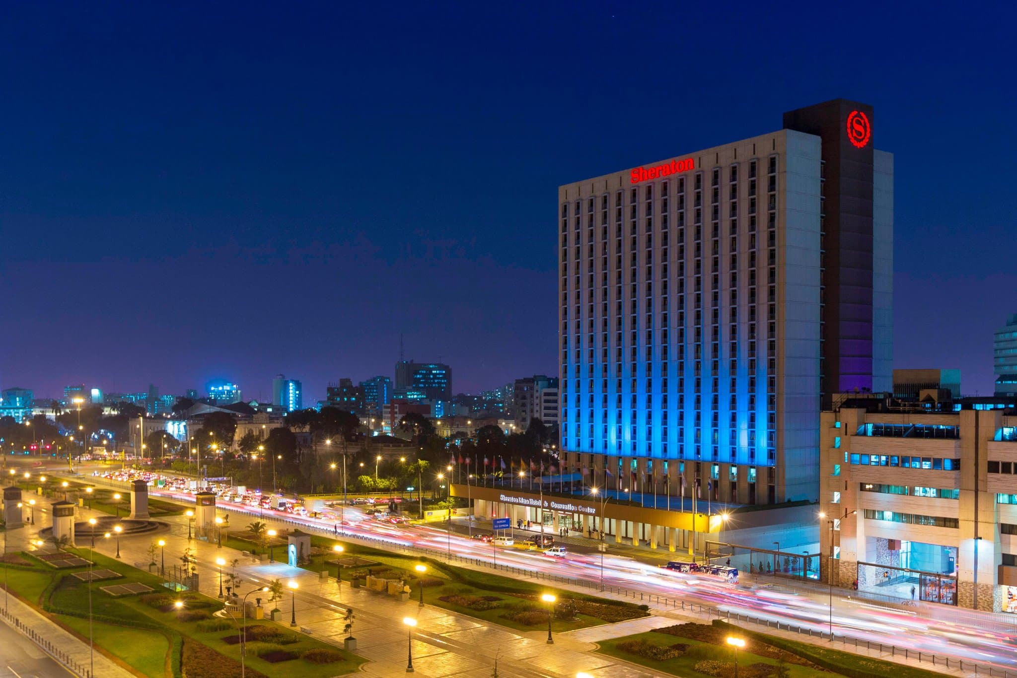 The imposing Brutalist exterior of the Sheraton Lima Historic Center rising above the city traffic, featuring its grand concrete balconies.