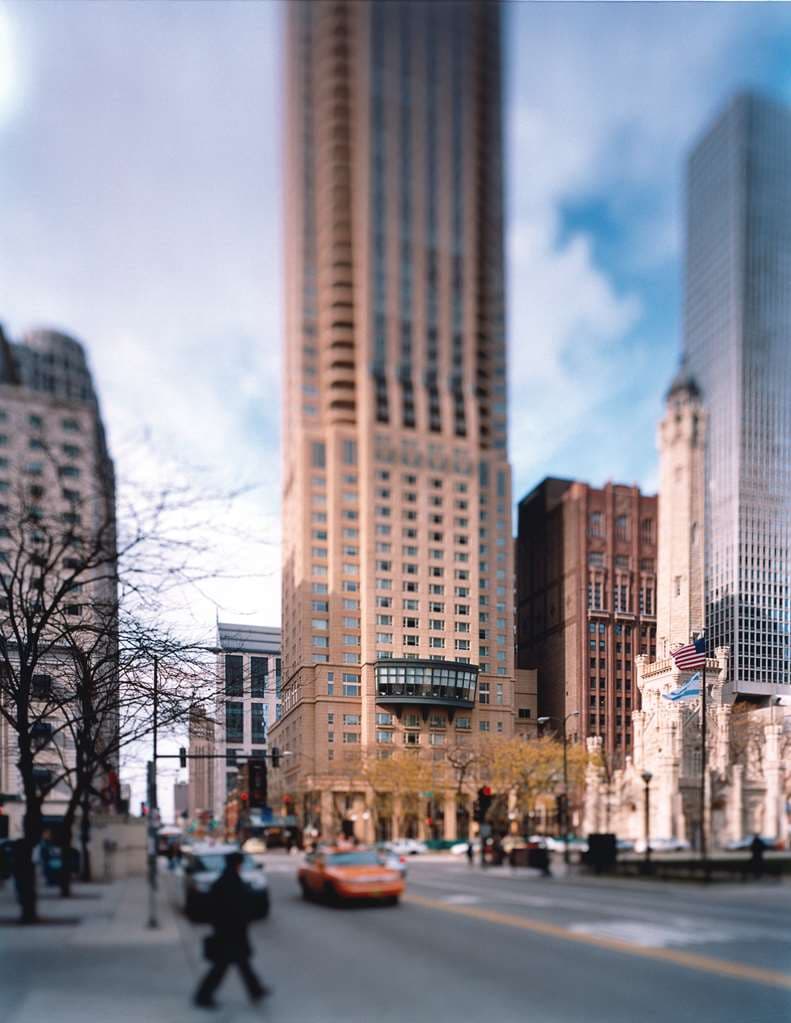 A guest relaxing in the signature cushioned window nook of a Park Hyatt Chicago room, overlooking the Historic Water Tower and city skyline.