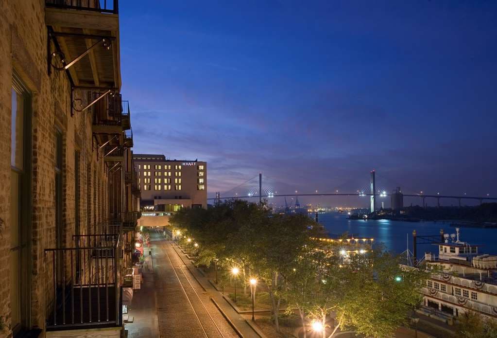 View from a Hyatt Regency Savannah balcony showing a massive cargo ship passing on the river with the Talmadge Bridge in the background.