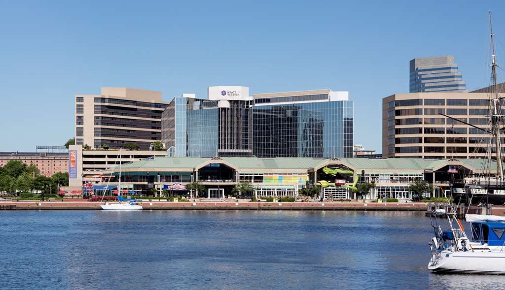 View of the Hyatt Regency Baltimore rooftop pool deck at sunset with the Inner Harbor and USS Constellation in the background.