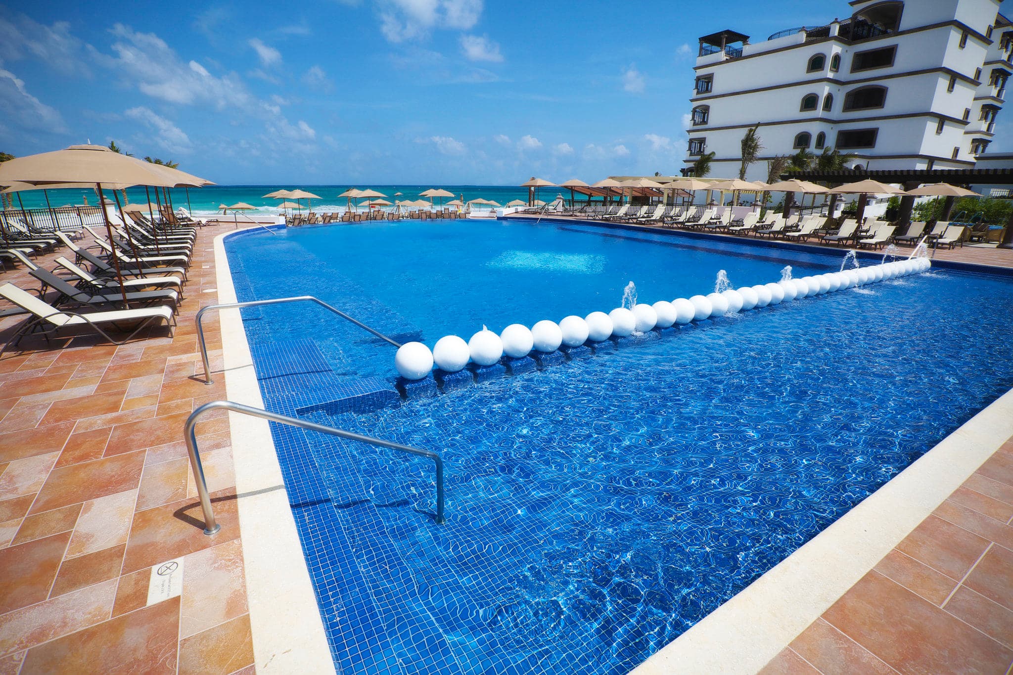 Infinity pool edge at Grand Residences Riviera Cancún overlooking the Caribbean Sea at sunrise.
