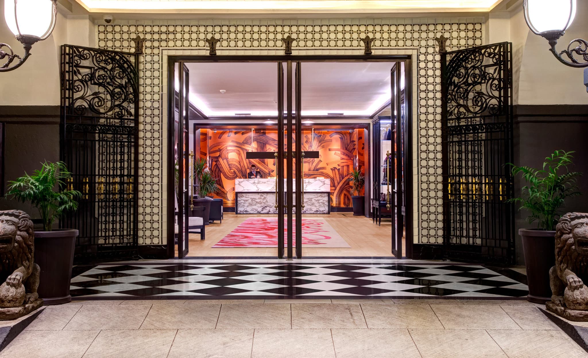Night view of the Four Seasons Mexico City central courtyard featuring a stone fountain with a lit fire ring, surrounded by colonial arches and lush greenery.