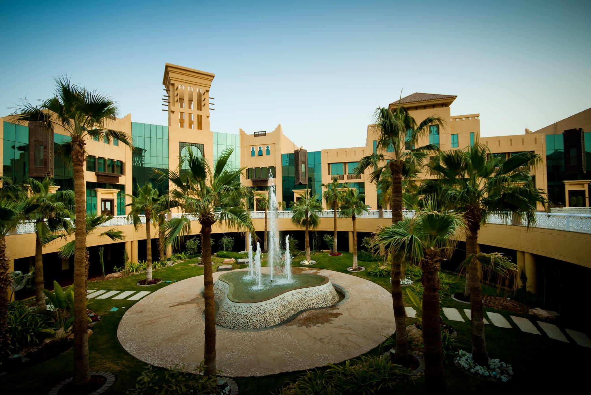 Arched sandstone hallways of Al Mashreq Boutique Hotel illuminated by warm lanterns at dusk.