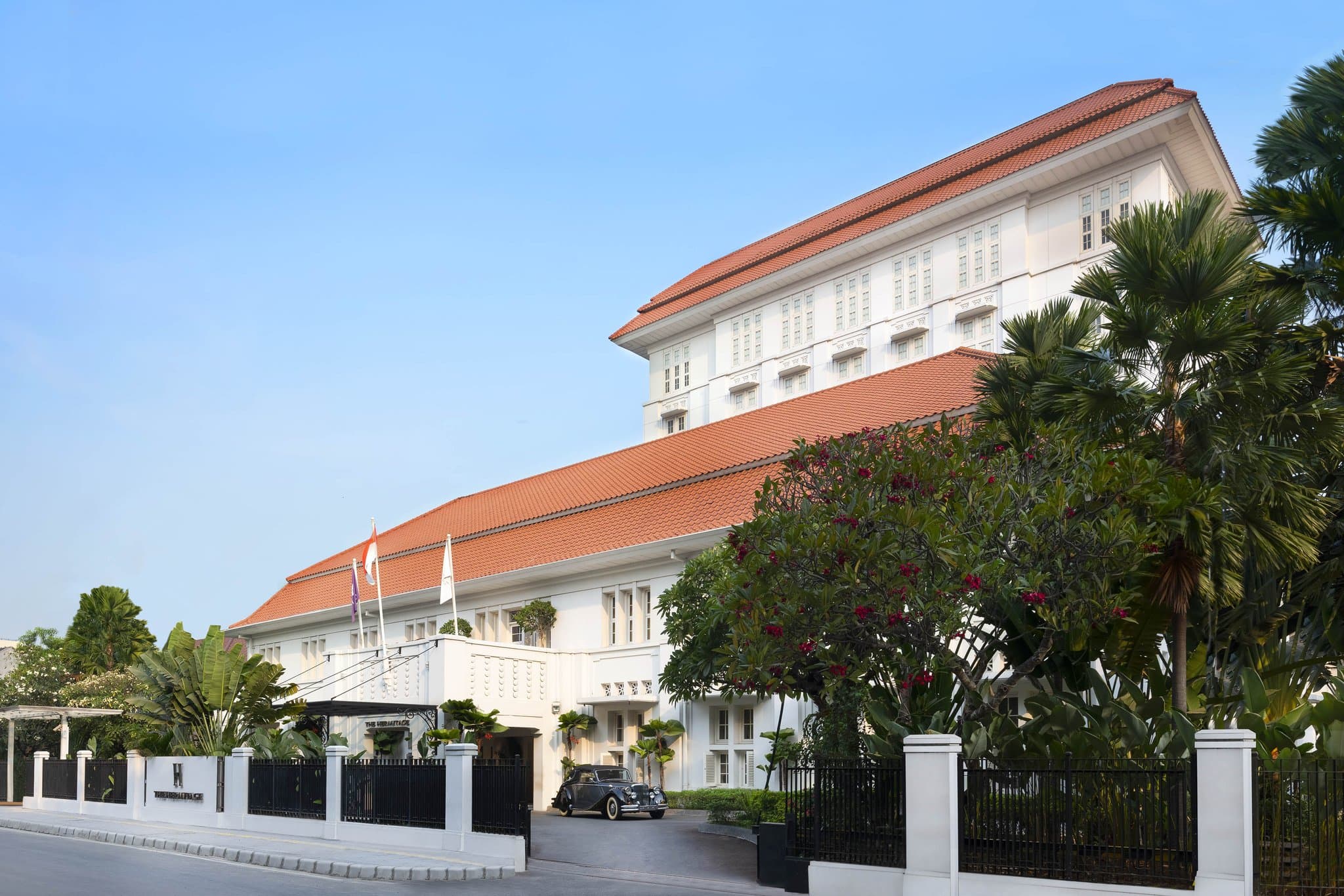 夕暮れ時にライトアップされたThe Hermitage Jakartaの白いアールデコ様式のファサード。