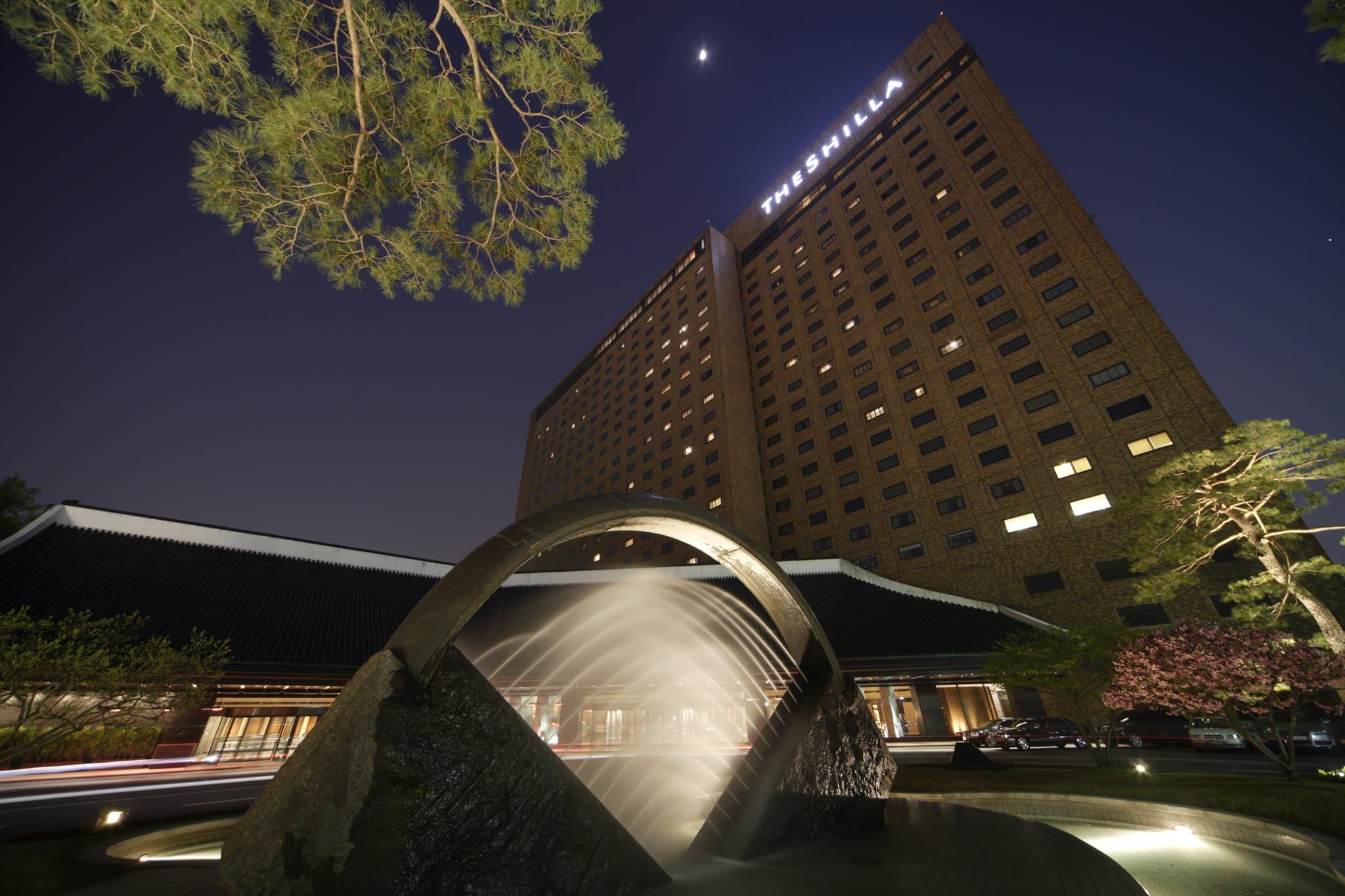 The Shilla Seoul's Urban Island outdoor pool deck at twilight with N Seoul Tower glowing in the background.