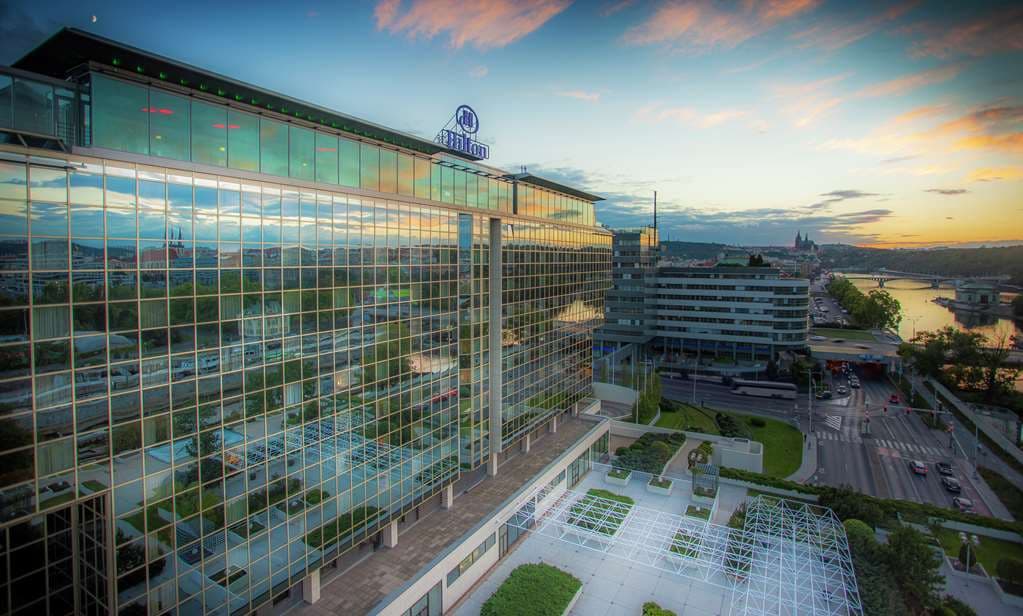 A view of the massive glass atrium lobby of Hilton Prague with the neon entrance to Cloud 9 visible.