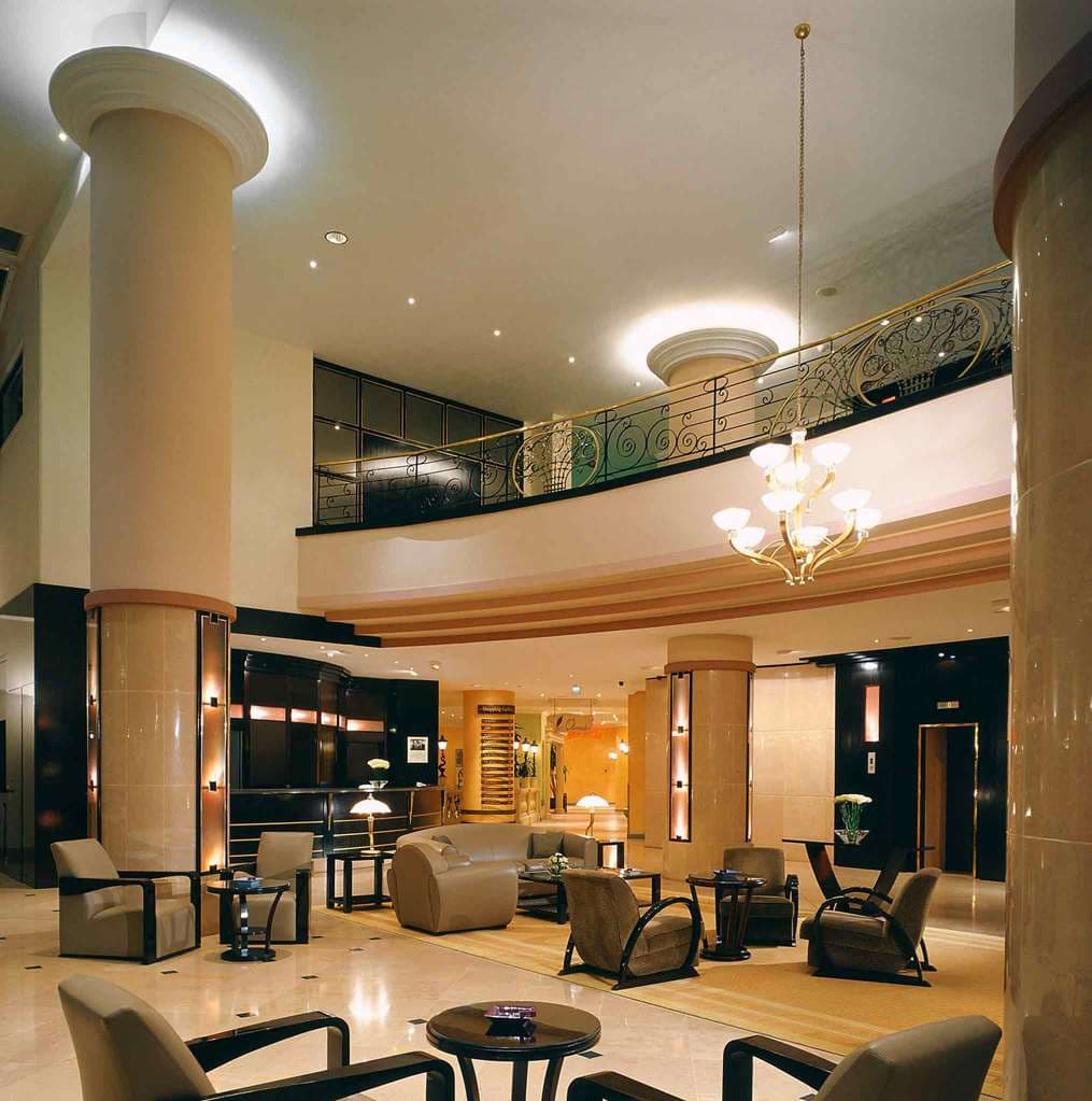 A sleek, modern hotel room at Pullman Bucharest with a large window overlooking the dense greenery of Herăstrău Park at sunrise.