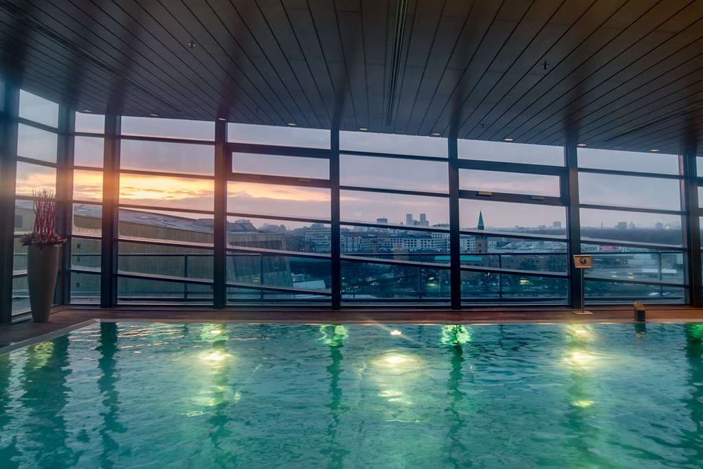 Grand Hyatt Berlin rooftop indoor pool with floor-to-ceiling windows overlooking the Berlin skyline at twilight.