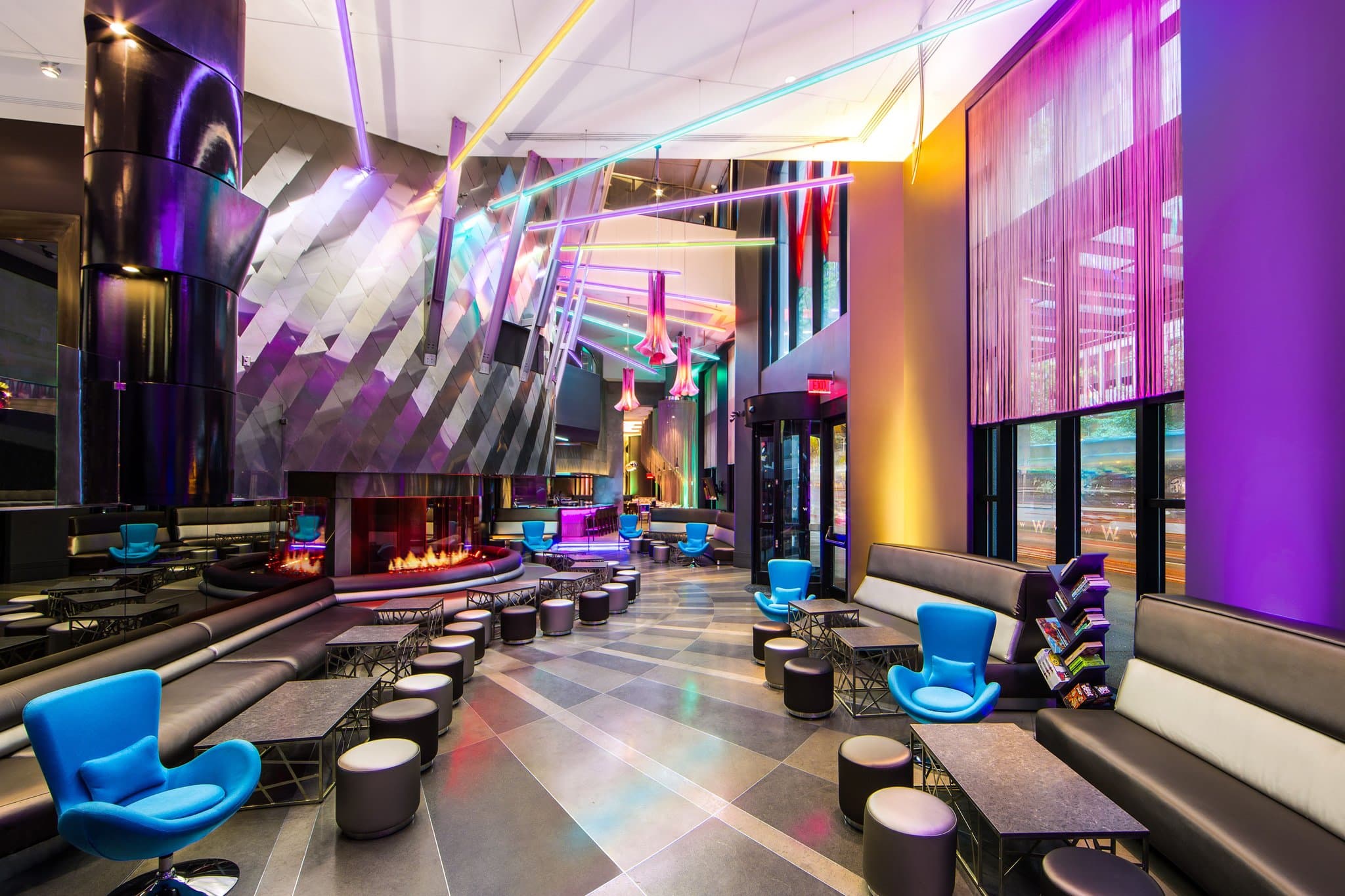 The W Seattle Living Room bar featuring a massive three-story stainless steel fireplace and modern, colorful lounge seating.