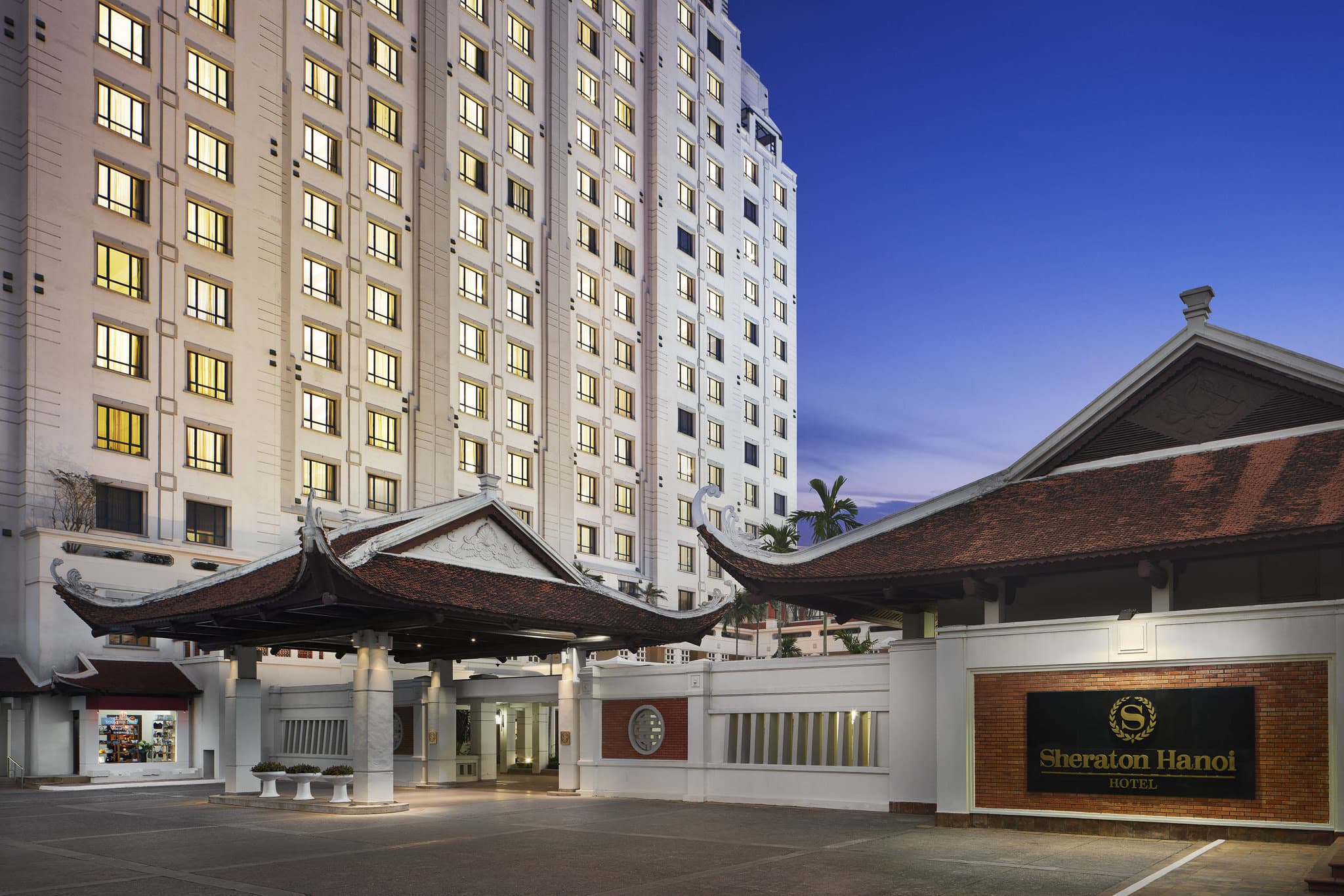 Sheraton Hanoi Hotel outdoor pool surrounded by lush tropical gardens and white lounge chairs near West Lake.