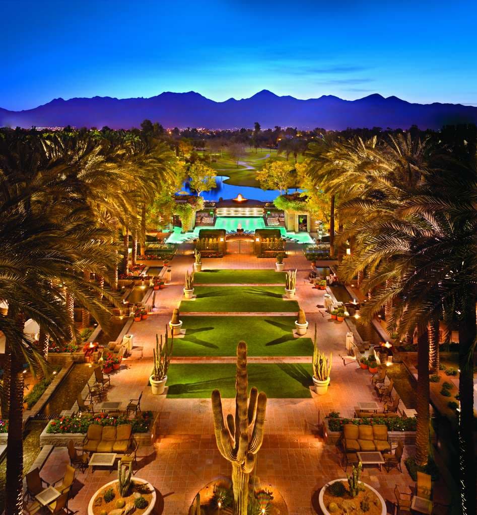Aerial view of the Grand Hyatt Scottsdale's 2.5-acre pool complex featuring a sand beach and cabanas against a desert mountain backdrop.