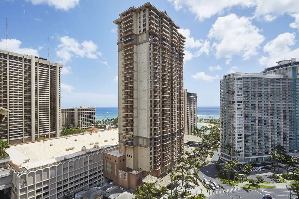View of the Paradise Pool with its 77-foot waterslide and waterfalls at the Grand Waikikian, surrounded by tropical landscaping.