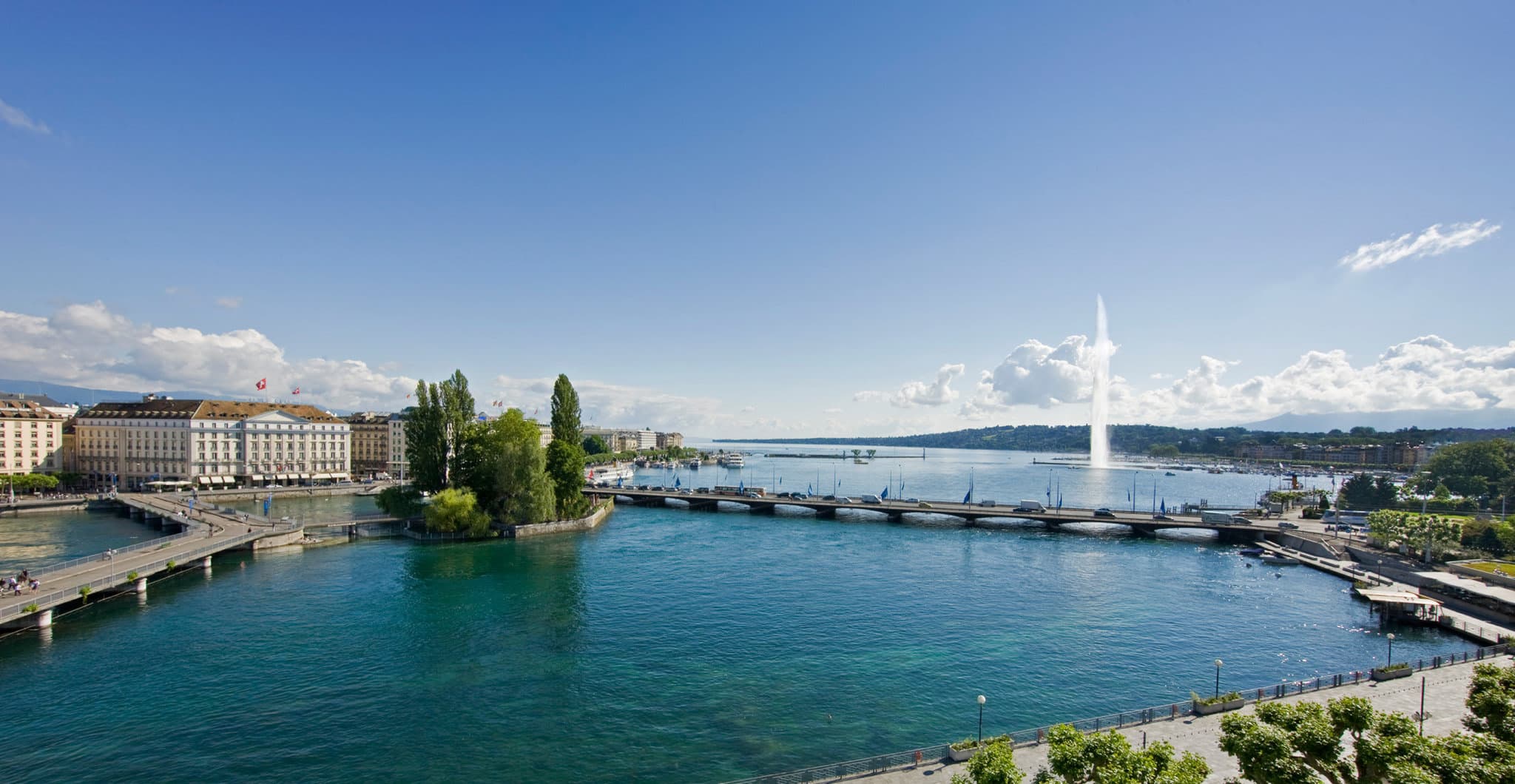 Rooftop infinity pool at Four Seasons Geneva with white columns and views of the snowy Alps through floor-to-ceiling windows.