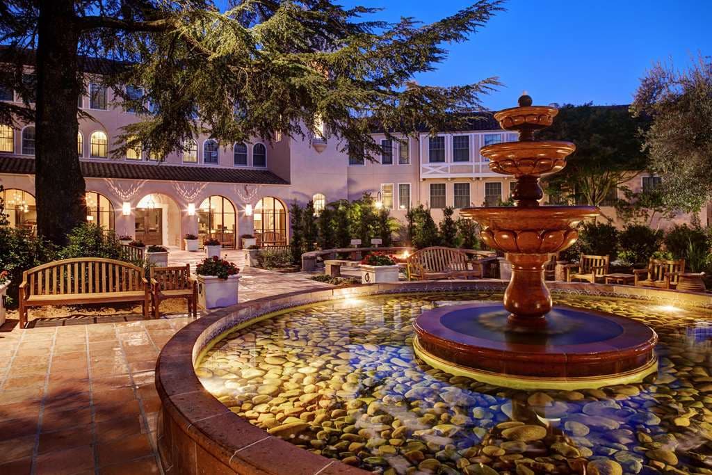 The iconic pink stucco water tower of Fairmont Sonoma Mission Inn rising above the steaming geothermal mineral pool at twilight.