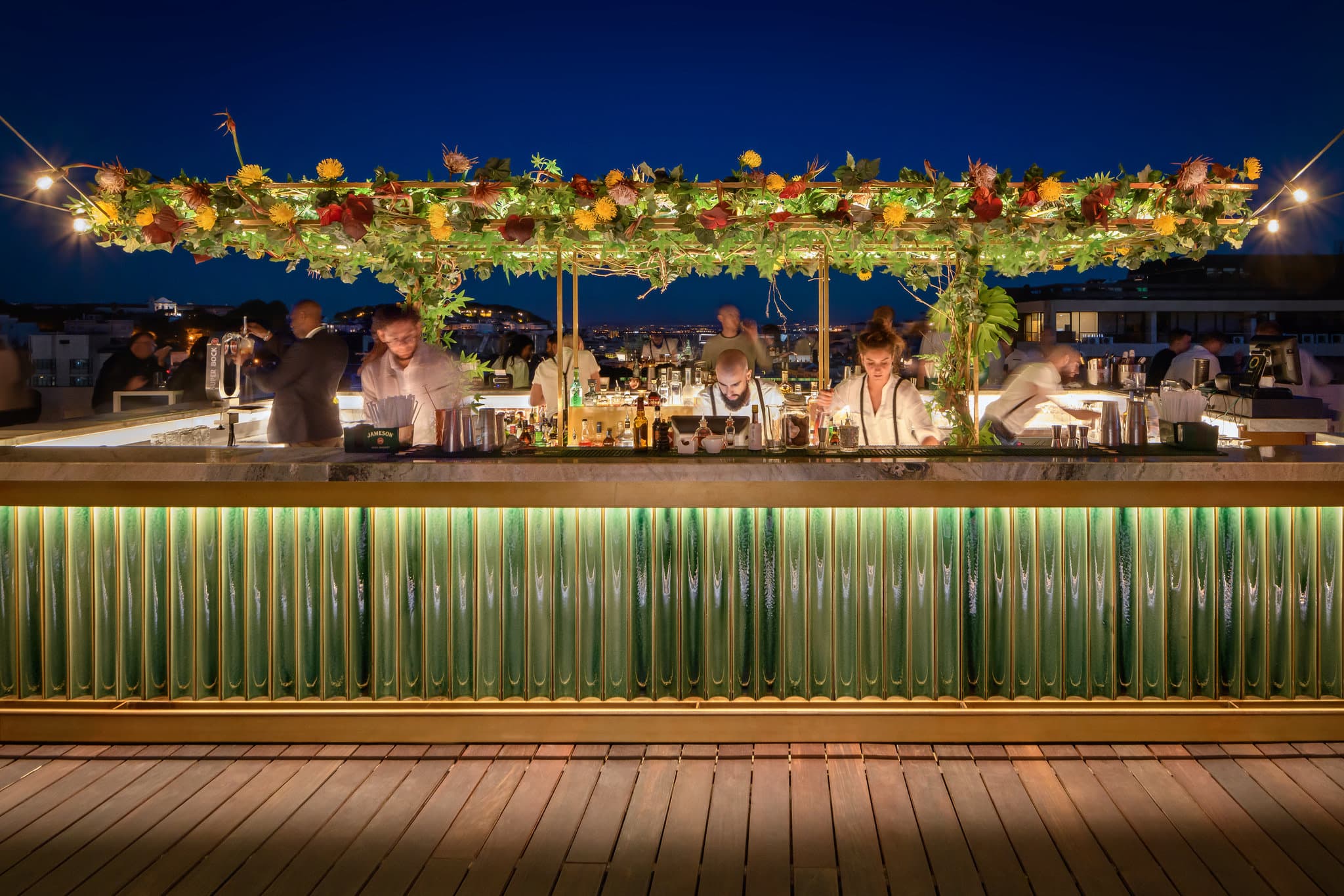The circular bar at SEEN Lisboa rooftop with a panoramic view of the Lisbon skyline and St. George's Castle at sunset.