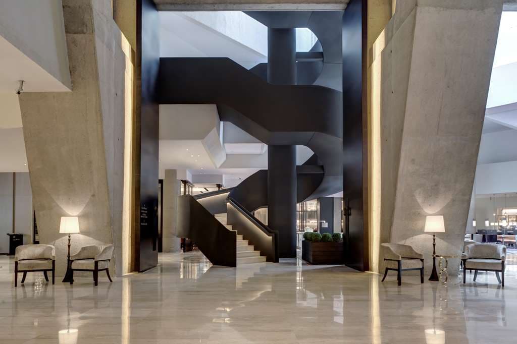 The soaring, brutalist-inspired atrium lobby of Hyatt Regency Mexico City featuring the spiral staircase and entrance to Rulfo restaurant.