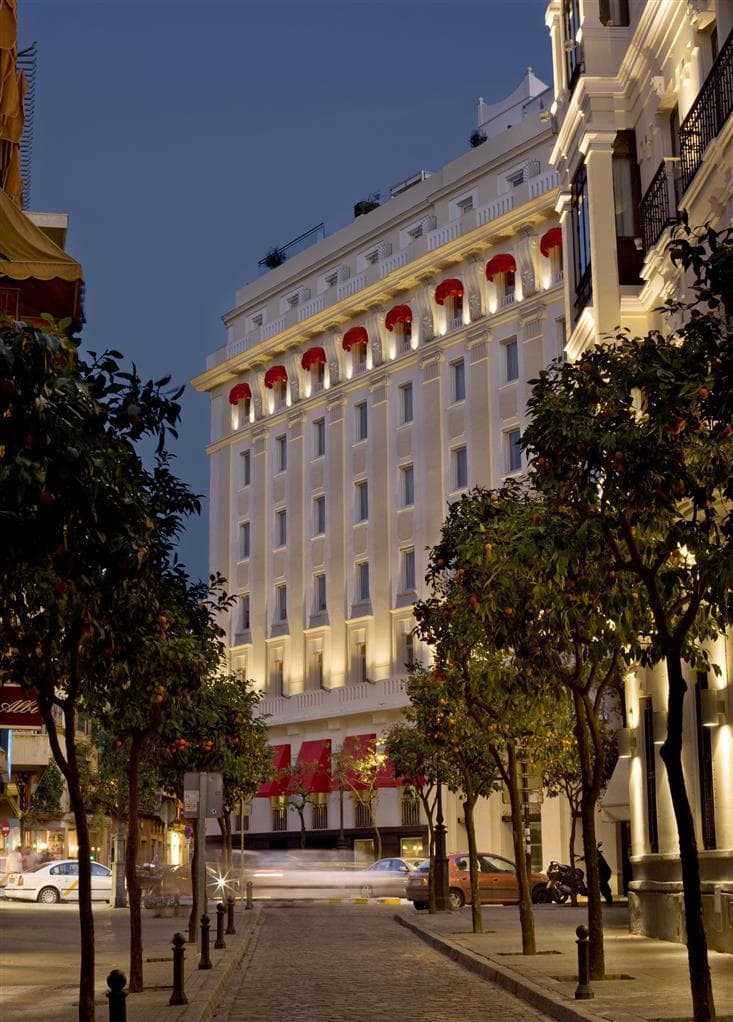 Low-angle view of the Hotel Colón Gran Meliá's illuminated stained-glass lobby dome with Art Nouveau details.
