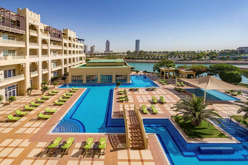 View of the Grand Hyatt Doha's traditional Arabian architecture and lush gardens framing the outdoor pools.
