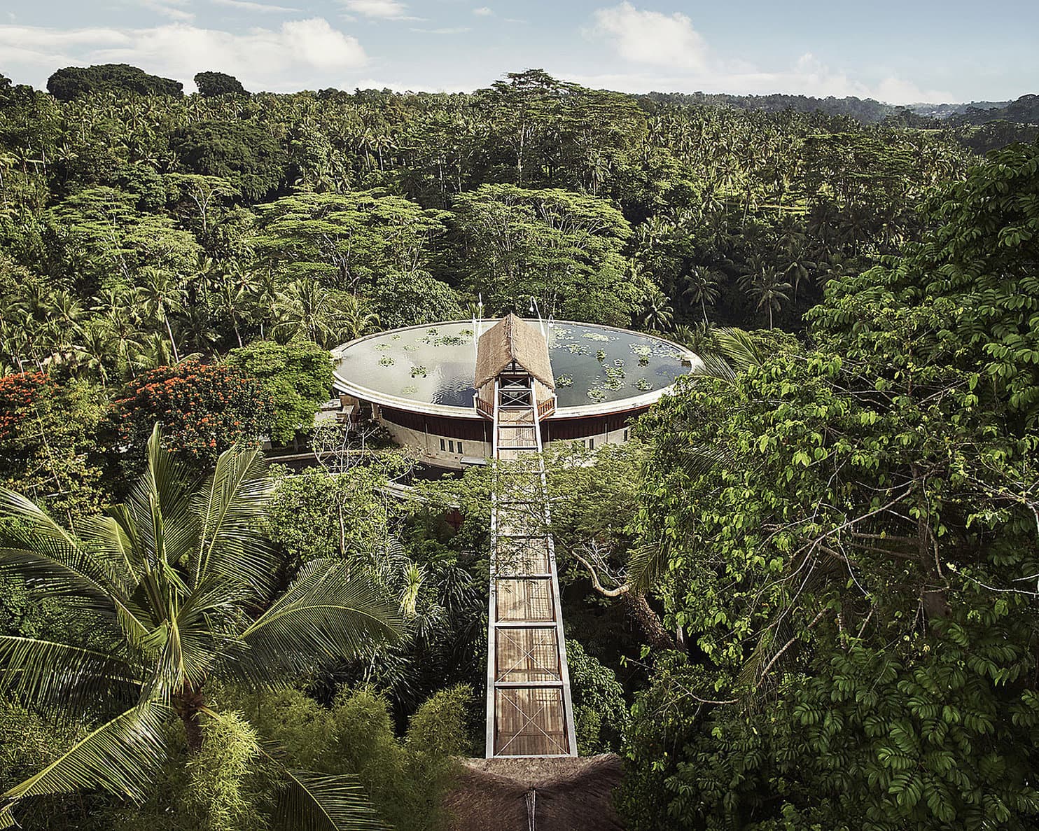 A dramatic suspension bridge leading to a lotus pond on the roof of the Four Seasons Sayan, surrounded by dense Balinese jungle.