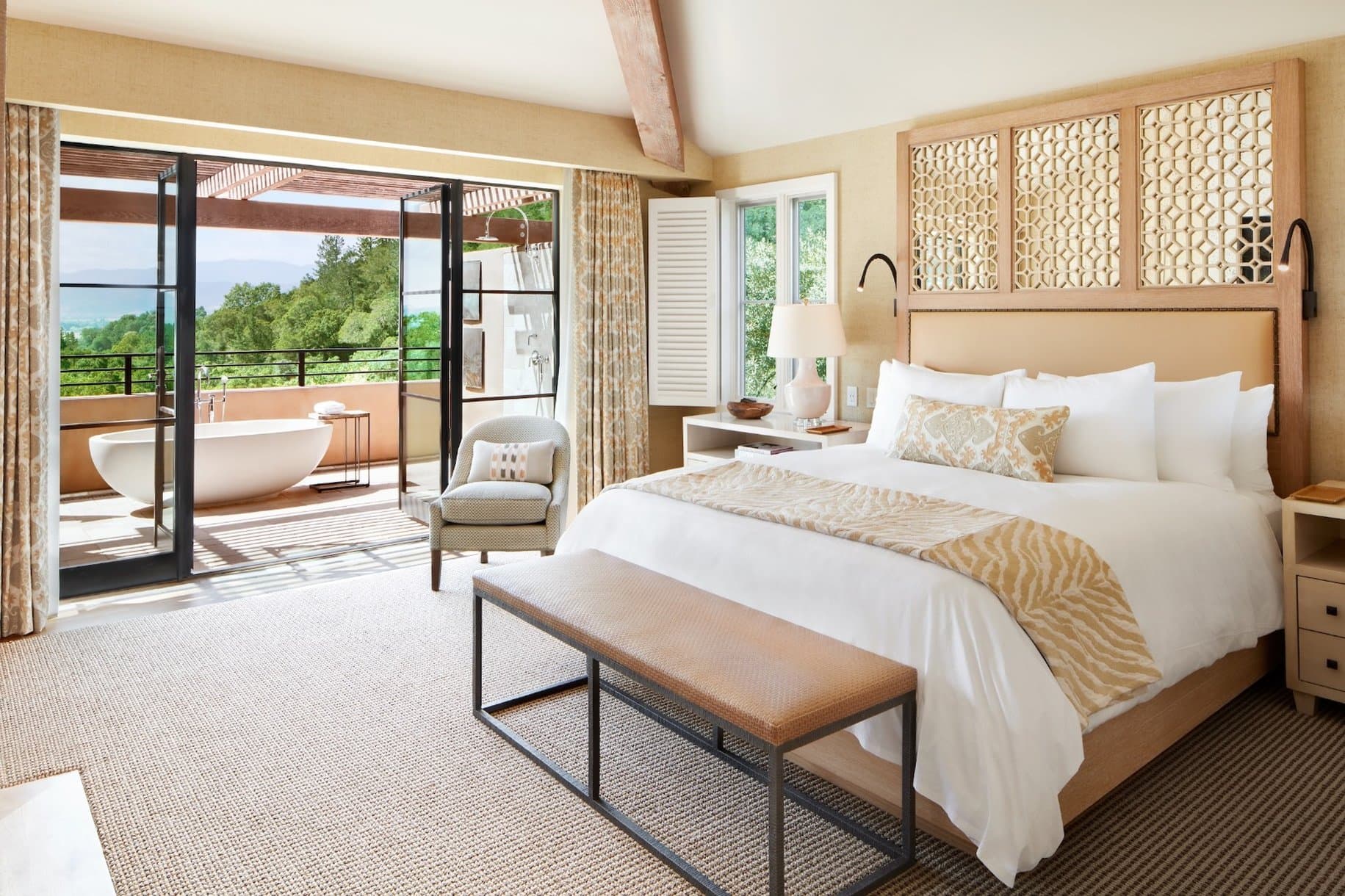 A sun-drenched private terrace at Auberge Du Soleil overlooking Napa Valley vineyards, featuring a breakfast table and olive trees.
