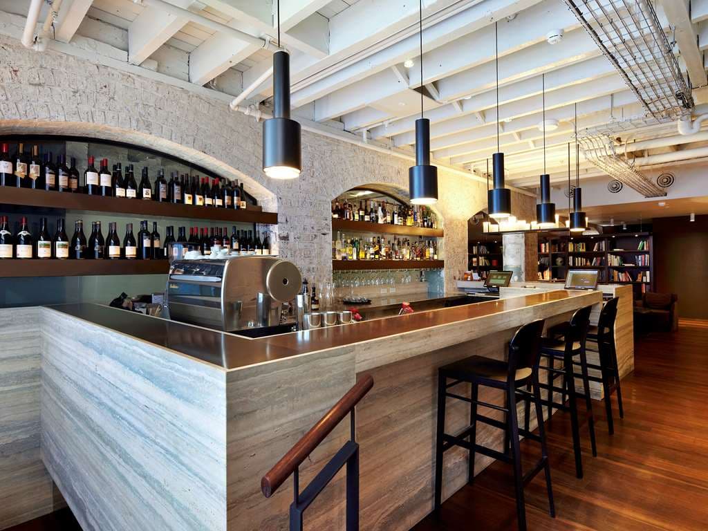 Exposed sandstone walls and moody lighting inside the Tayim Restaurant at Harbour Rocks Hotel.