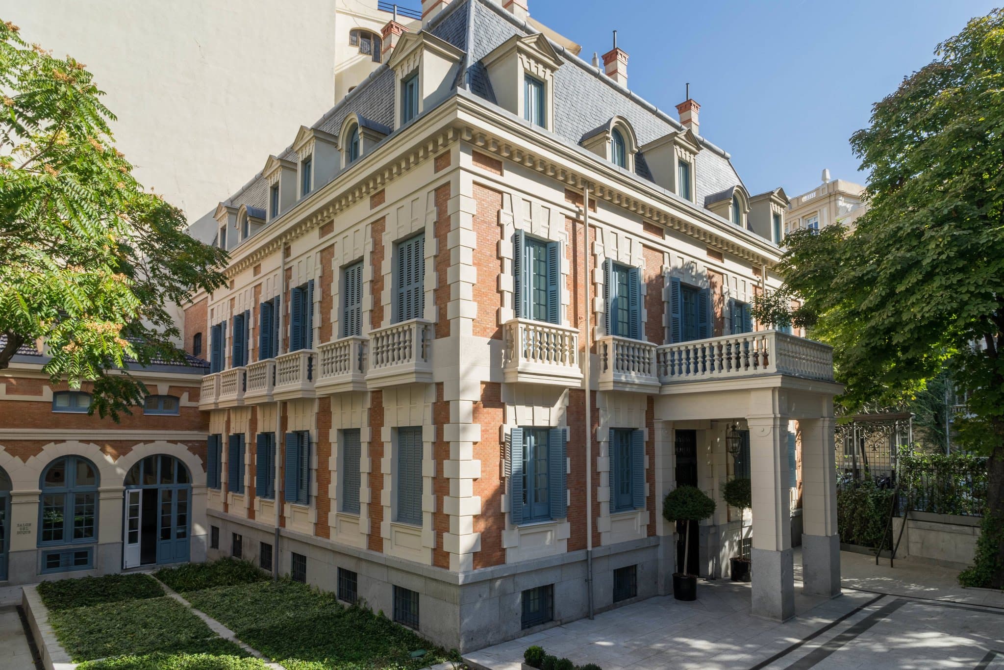 The lush garden terrace of Santo Mauro Hotel featuring Parma Gray iron furniture surrounded by mature trees and the 19th-century French Neo-classical facade.