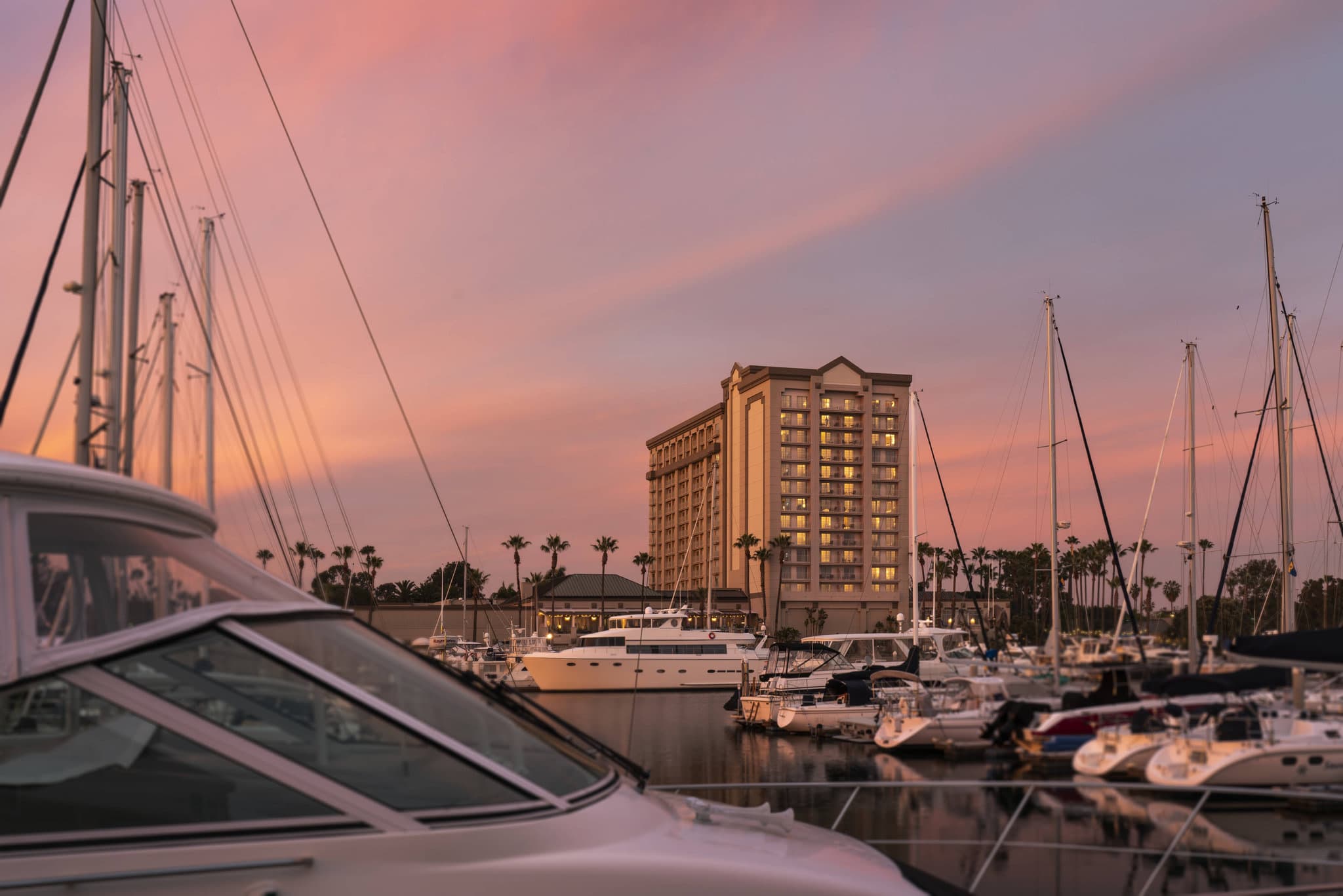 Cast & Plow outdoor terrace at dusk featuring fire pits, lounge seating, and a backdrop of docked yachts in Marina del Rey.