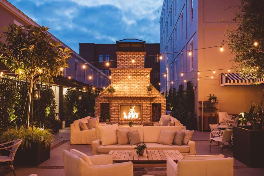 The Emeline Hotel courtyard featuring a large brick fireplace, string lights, and guests dining at Frannie & The Fox.