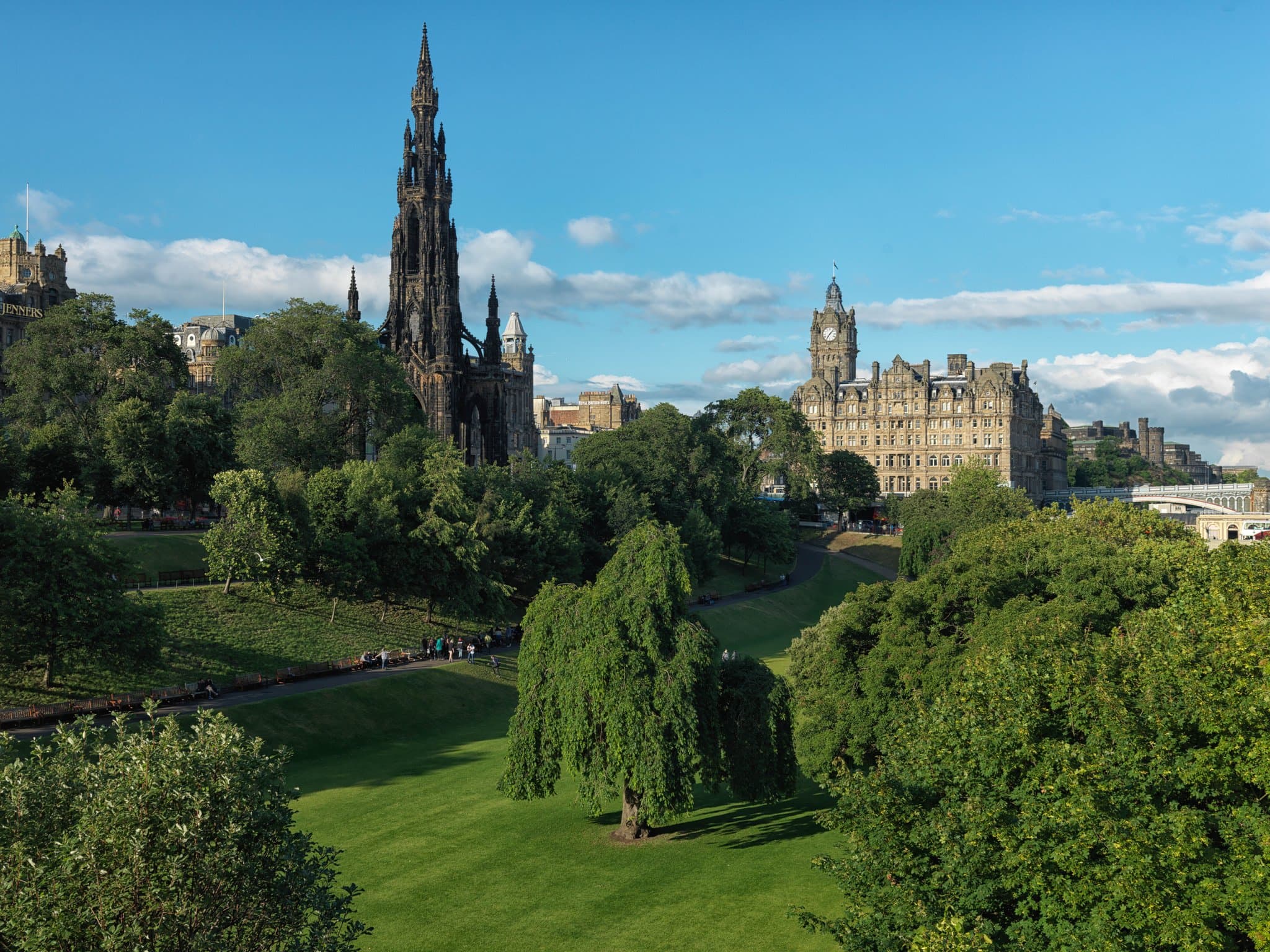 The Balmoral Hotel's iconic clock tower rising above Edinburgh's Old Town skyline at dusk.