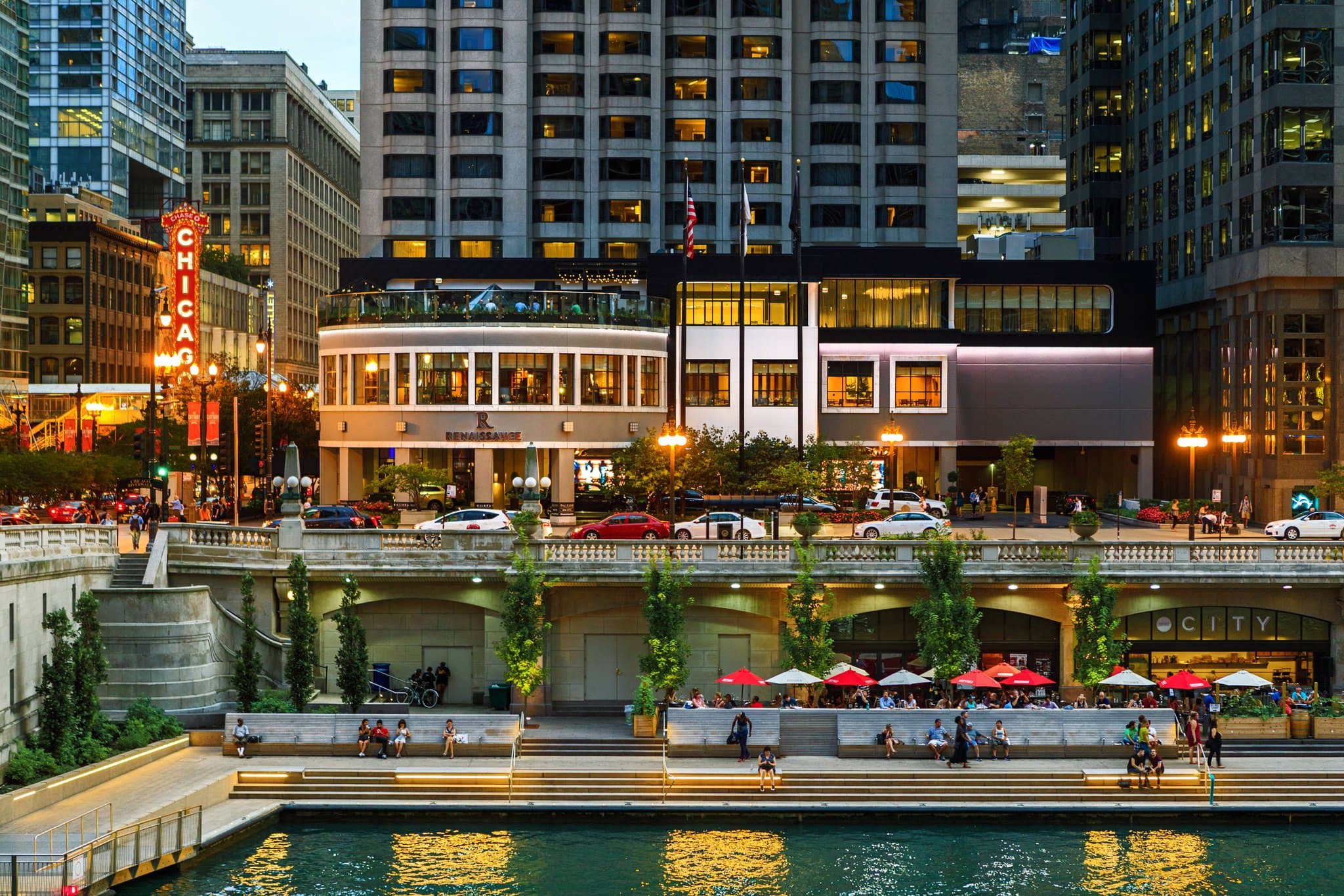 View from Raised rooftop bar at Renaissance Chicago Downtown featuring fire pits, guests with cocktails, and the Chicago river bridges at sunset.