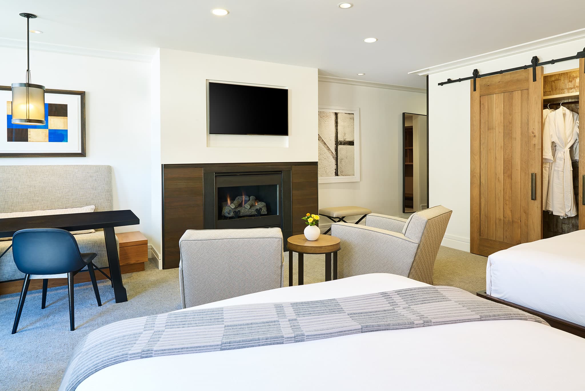 The Little Nell living room featuring a double-sided stone fireplace and contemporary art with soft cream furniture.