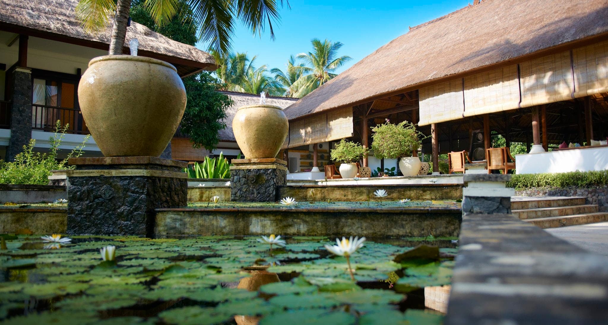 Infinity pool at Spa Village Resort Tembok Bali merging with the black volcanic sand beach and deep blue ocean.