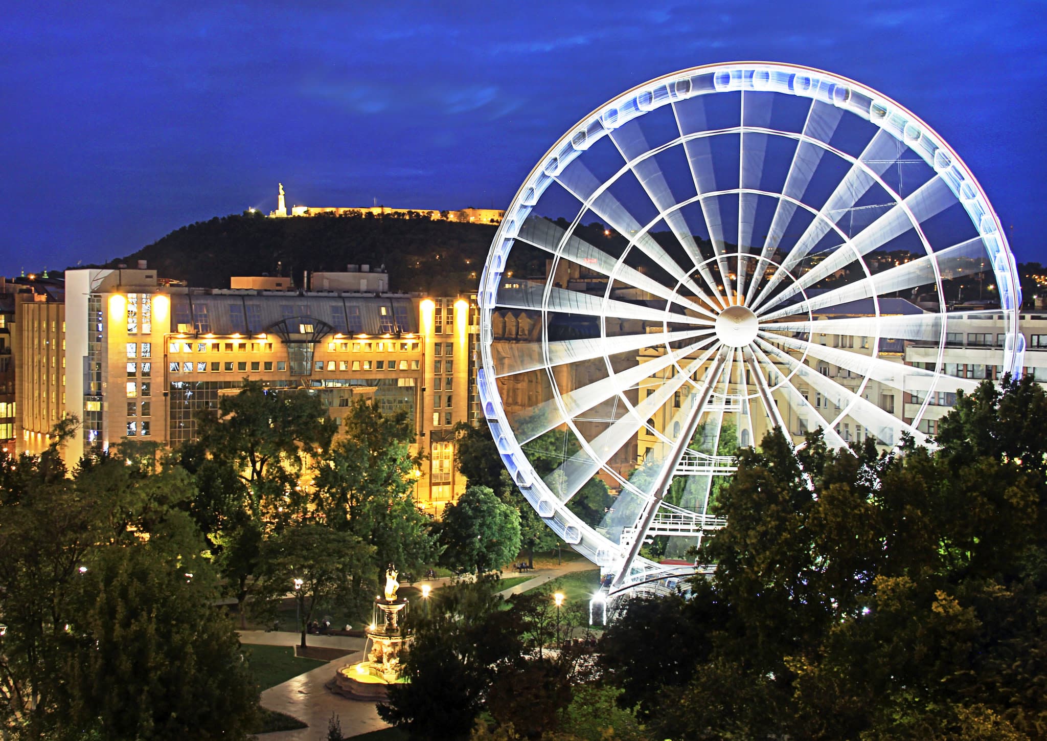 The illuminated Budapest Eye ferris wheel seen through the window of a renovated Park View room at Kempinski Hotel Corvinus.