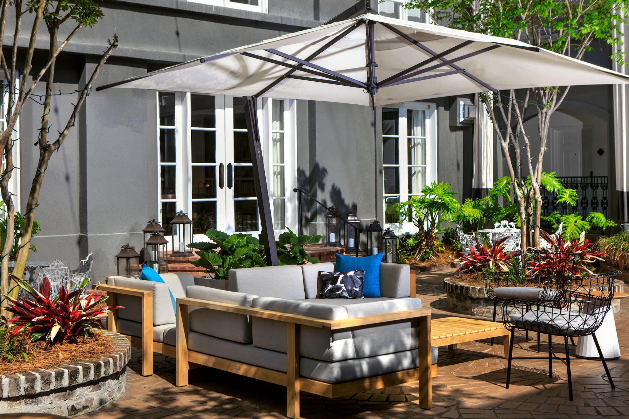 The Kimpton Brice Hotel's Secret Garden pool courtyard surrounded by lush greenery and lounge chairs.