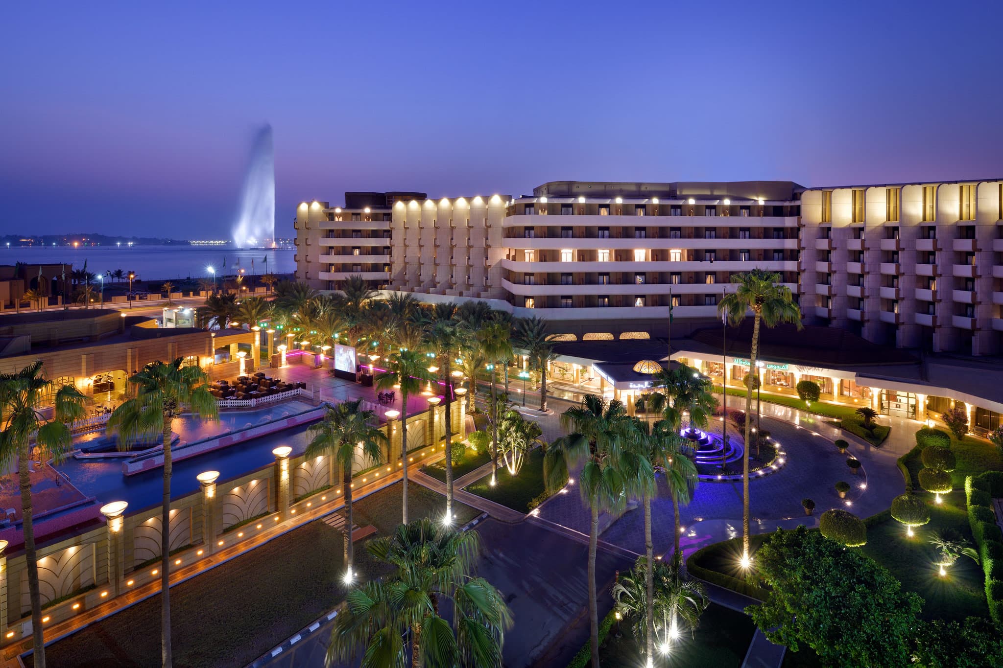 View from InterContinental Jeddah balcony overlooking the pool deck and the King Fahd's Fountain spraying water at sunset.