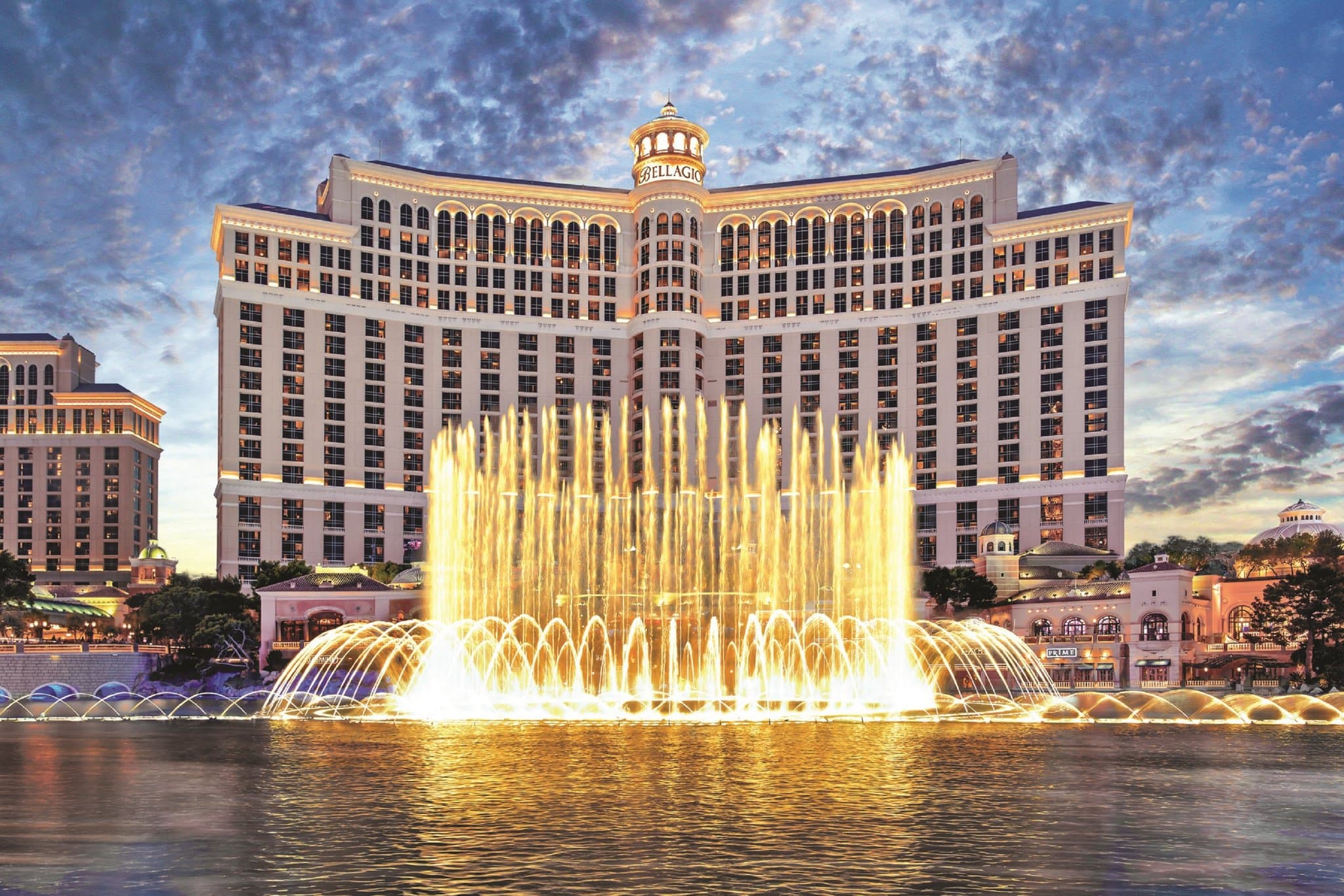 A private Bellagio Villa terrace at twilight featuring a personal pool and manicured gardens, with the illuminated Bellagio Fountains erupting in the immediate background.
