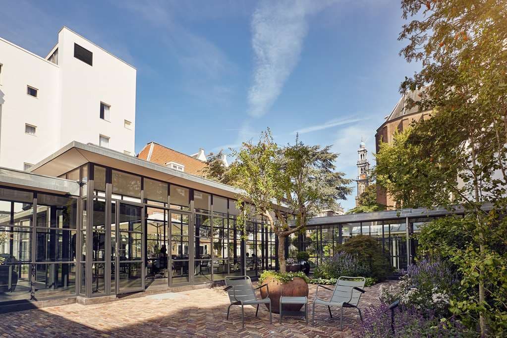 The Pulitzer Amsterdam's lush inner garden courtyard surrounded by historic brick canal houses.