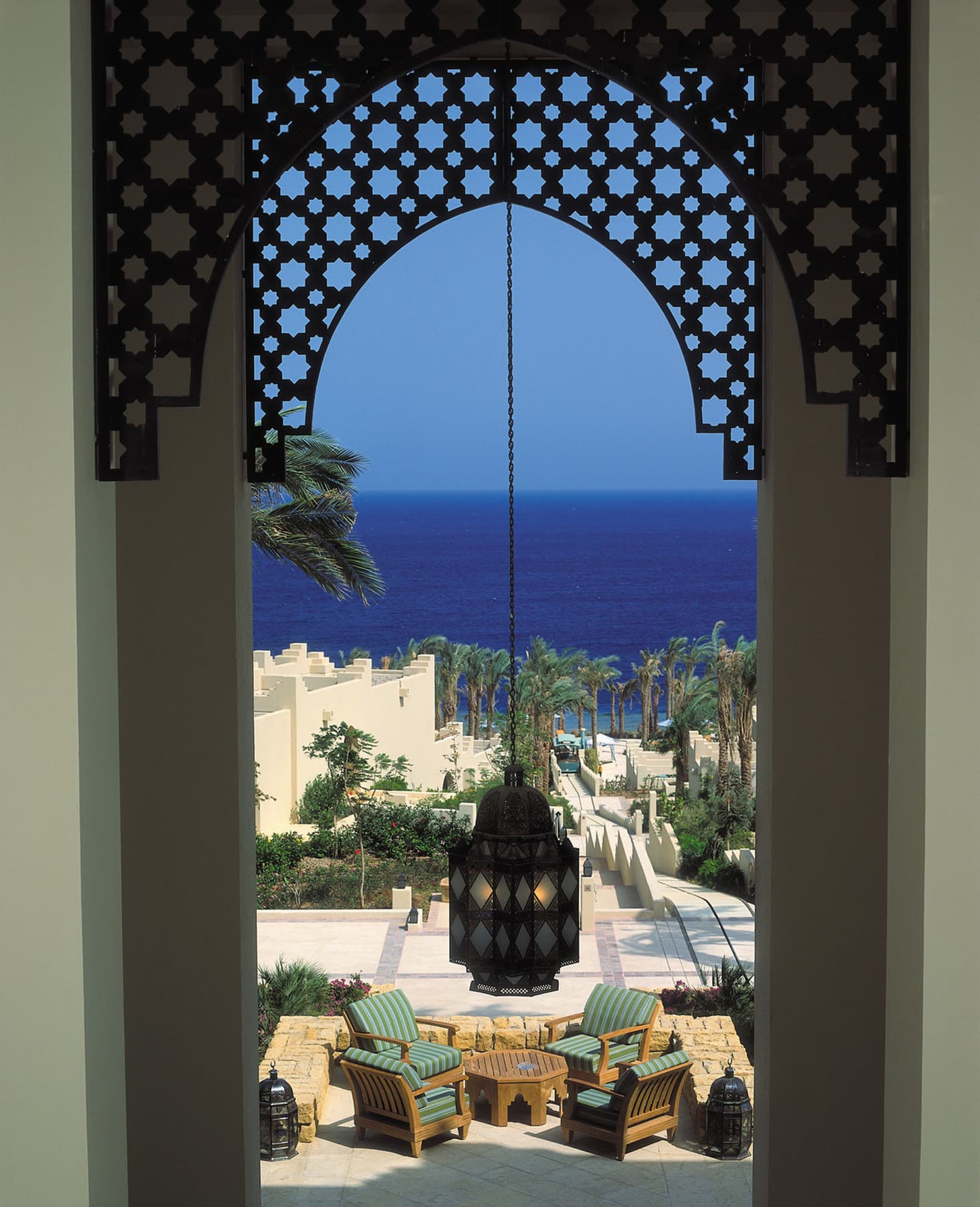 A diver descending from a private wooden jetty at Four Seasons Sharm El Sheikh, with the Red Sea coral reef visible beneath clear turquoise water.