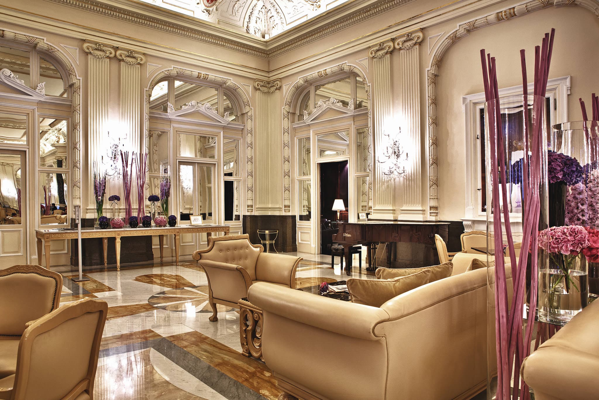 A grand, 20-meter indoor lap pool with a vaulted ceiling and mosaic floor, illuminating the neo-Renaissance architecture of the NH Collection Prague Carlo IV wellness center.