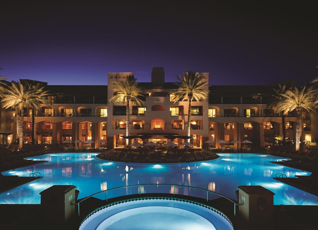 Sunset Beach pool at Fairmont Scottsdale Princess featuring real white sand, palm trees, and lounge chairs with the McDowell Mountains in the distance.