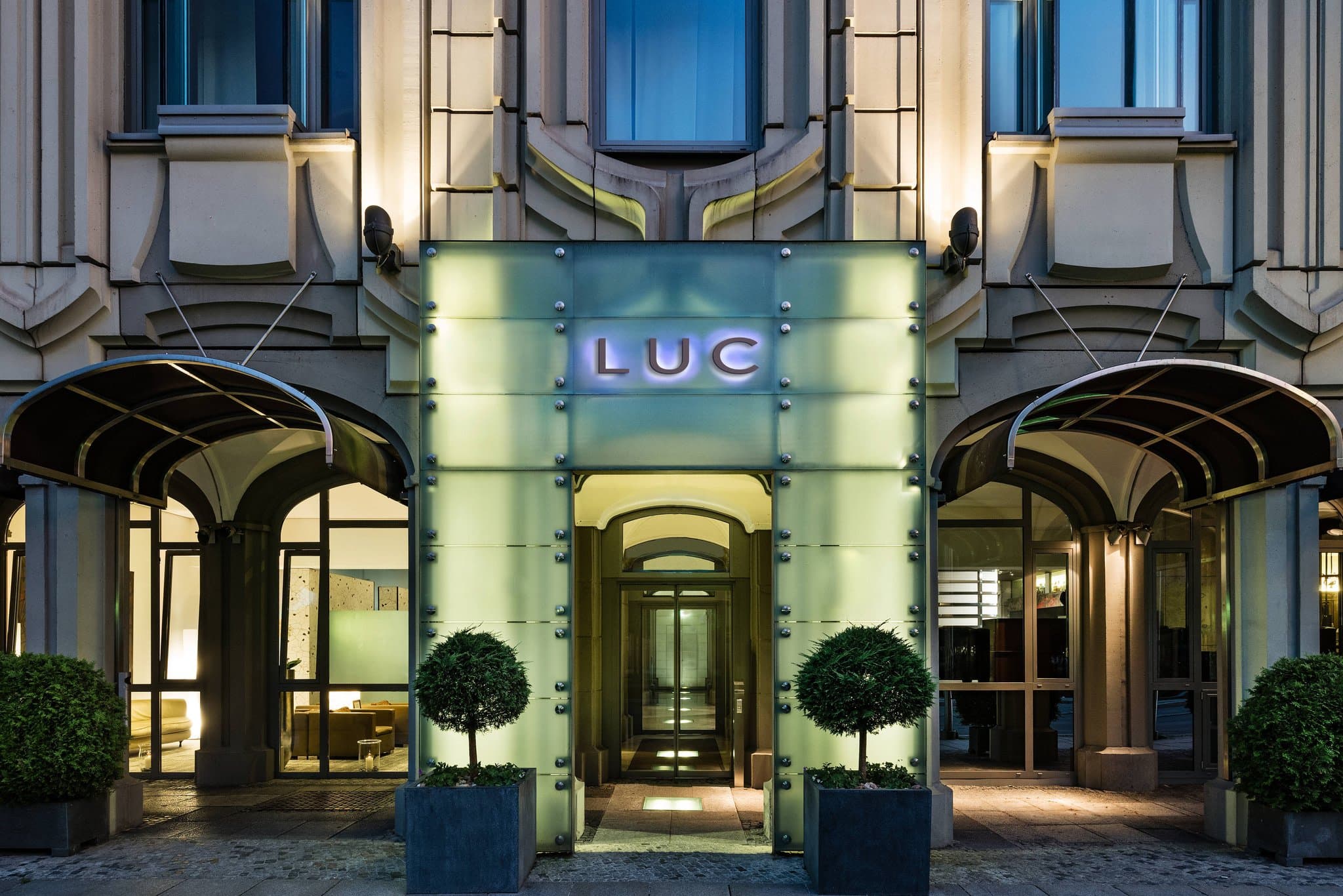 Hotel Luc Berlin lobby featuring deep Prussian blue decor, geometric rugs, and a signature pop-art portrait of a Prussian figure.
