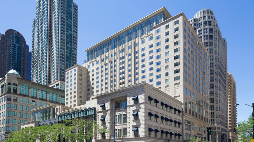 The Peninsula Chicago's 19th-floor indoor pool with floor-to-ceiling windows overlooking the snowy Chicago skyline.