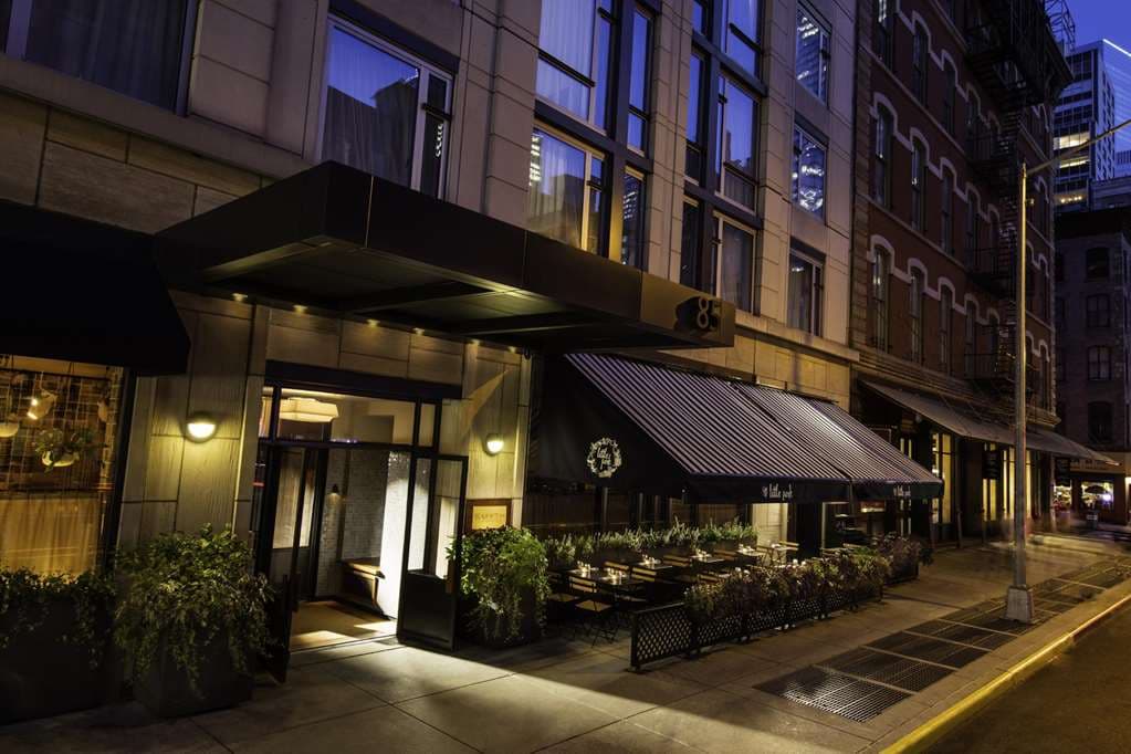 Smyth Tribeca Galerie Bar featuring a cozy fireplace, mid-century modern armchairs, and warm amber lighting.