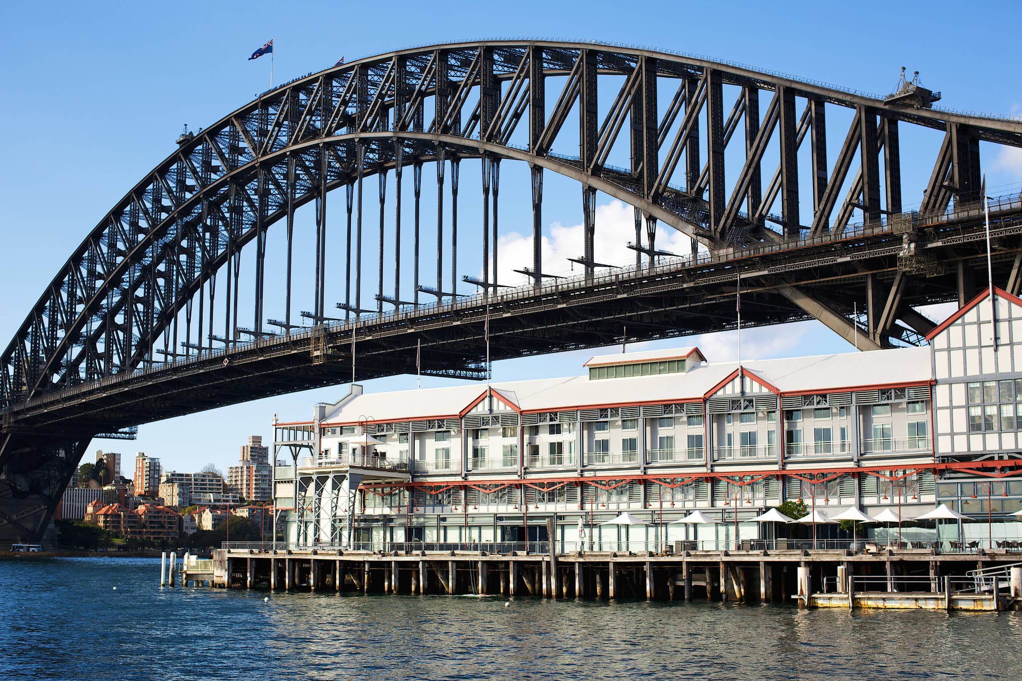 A luxurious bathtub in the Admiral Suite at Pier One Sydney Harbour, framed by large windows with a direct, close-up view of the Sydney Harbour Bridge steelwork.