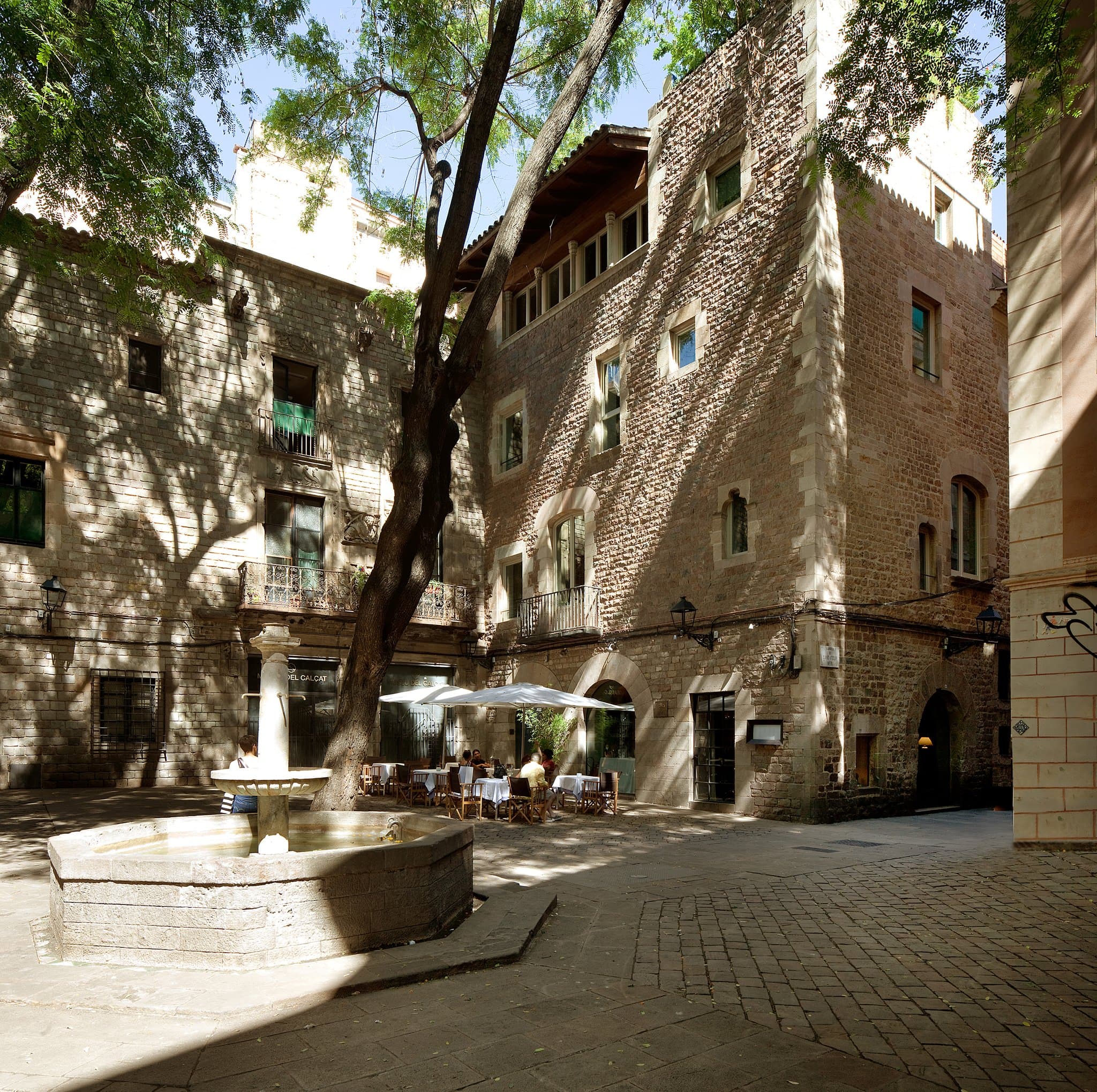 The moody, stone-walled interior of 'a Restaurant' at Hotel Neri featuring 17th-century arches and velvet seating.